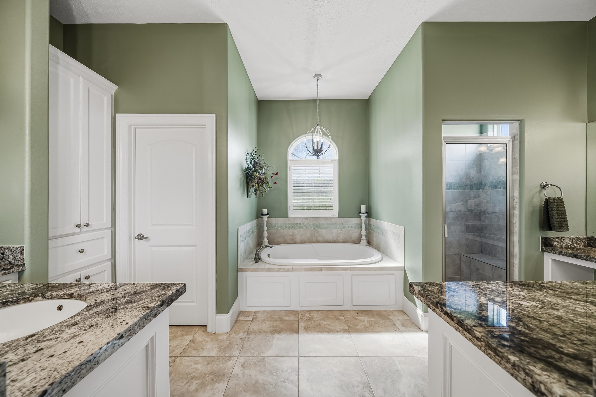 Unwind in the tranquil comfort of this spa-inspired Primary Bathroom, where rich, moody green tones create a warm and relaxing ambiance. Crisp white cabinetry provides a striking contrast, lending the space a bright, polished elegance that feels both timeless and refined.