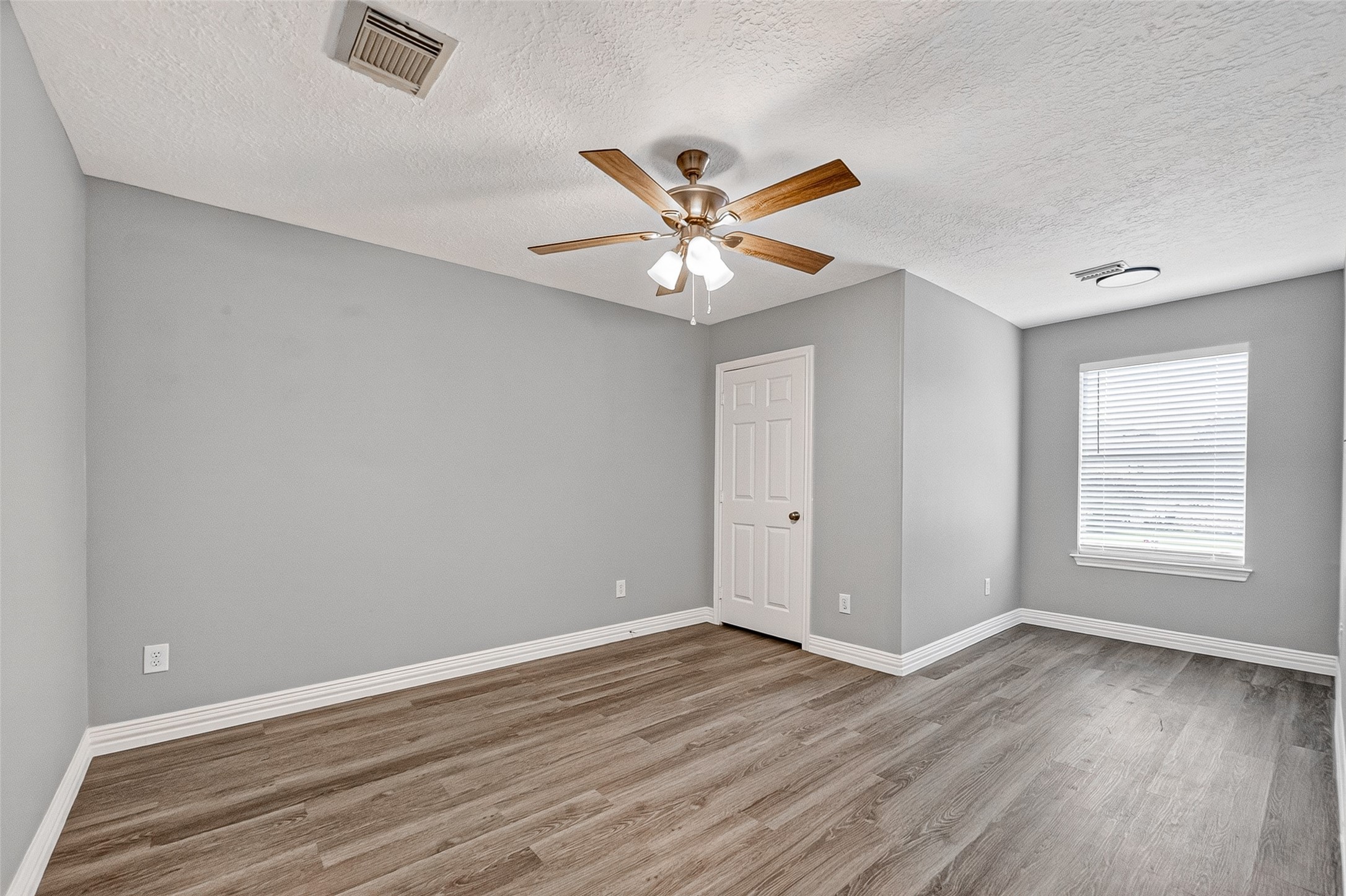 Spacious bedroom with ceiling fan and natural light