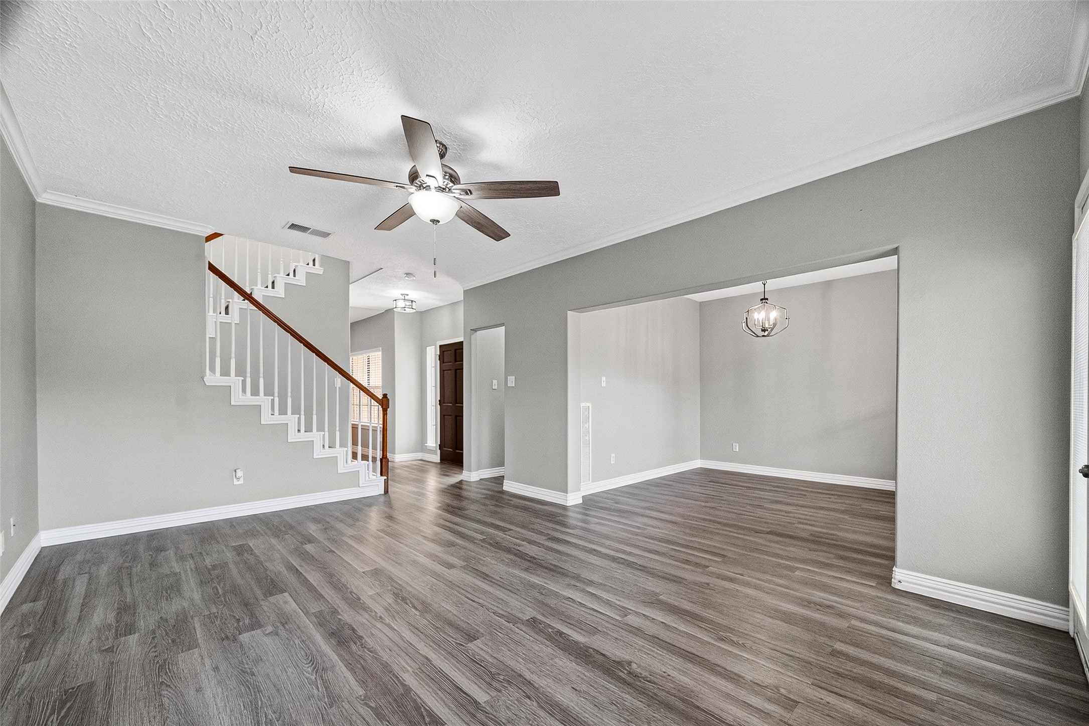 Spacious living area with staircase and ceiling fan