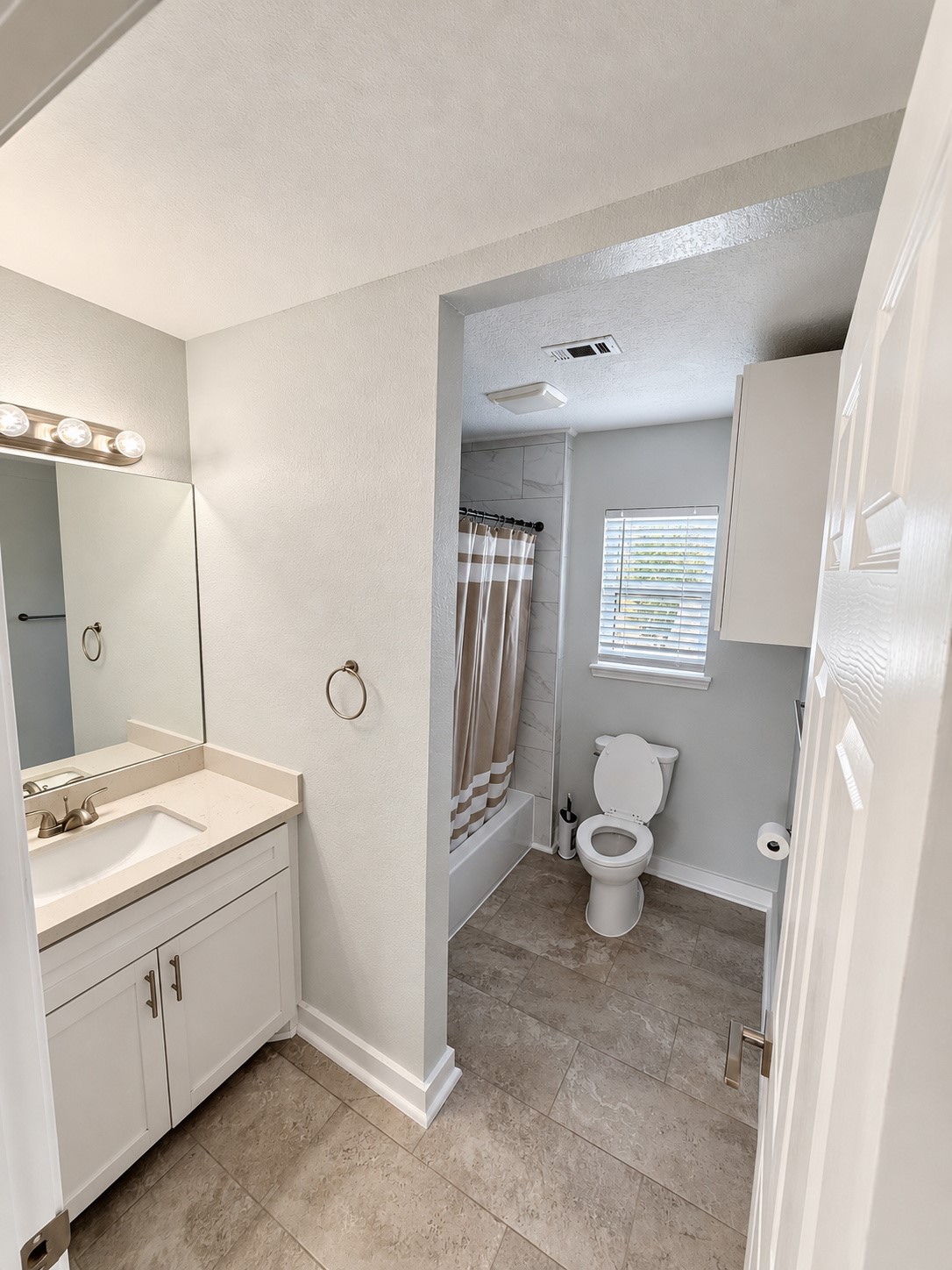 Bathroom with a separate vanity area and tub/shower combination.