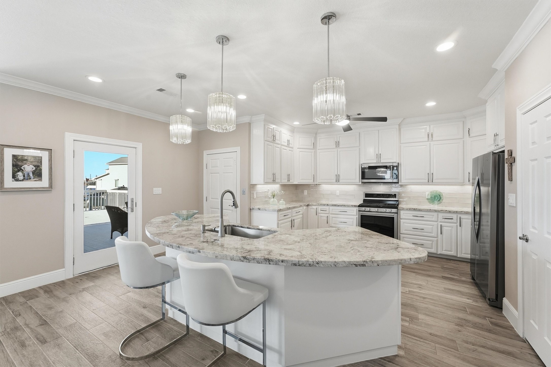 The generous island creates a natural centerpiece for the open kitchen, offering bar seating, ample prep space, and an easy connection to the dining and living areas.