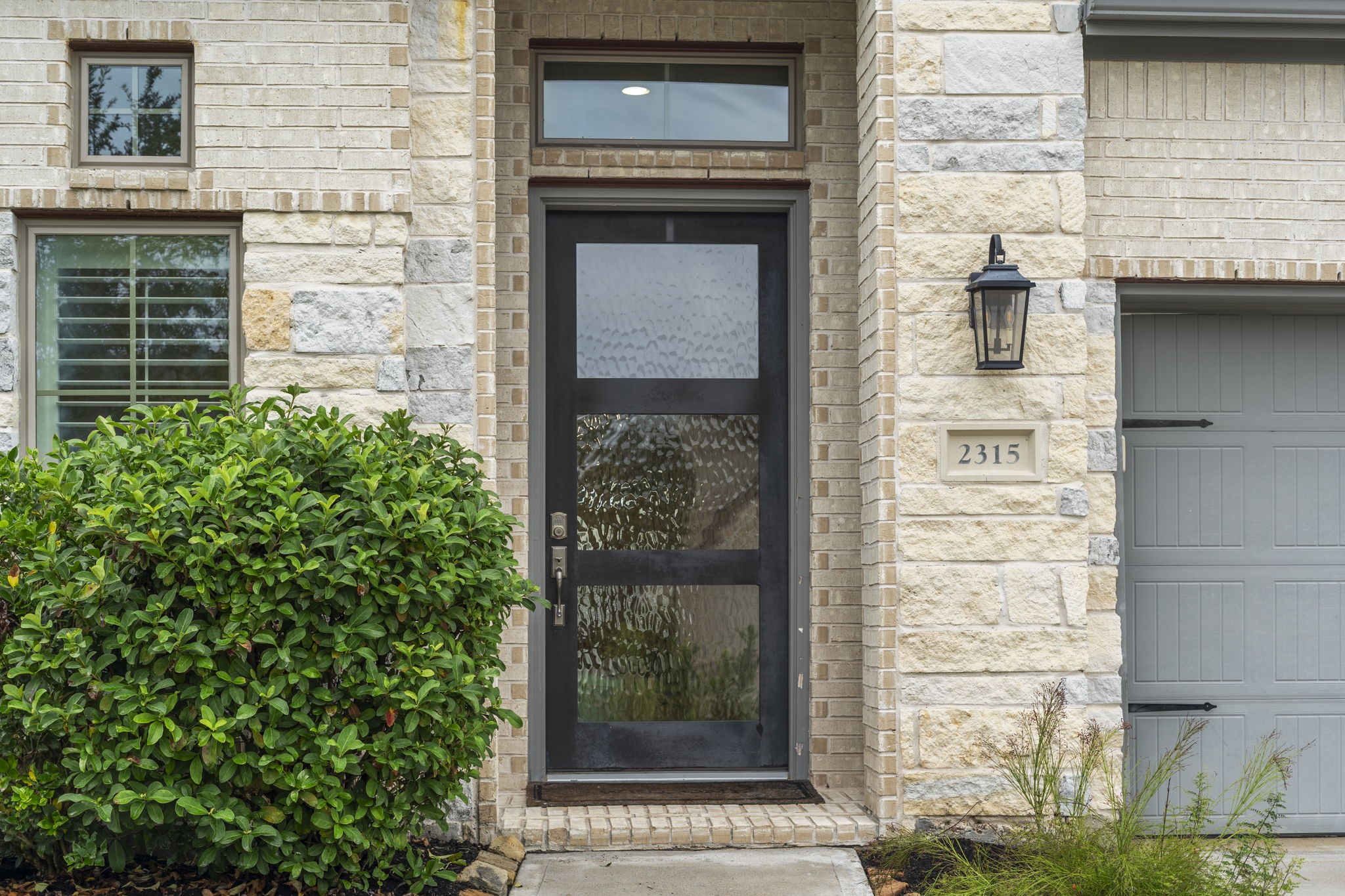 A striking black front door with stylish obscure glass and a transom window adds a sleek, modern touch. A striking black front door with stylish obscure glass and a transom window adds a sleek, modern touch.