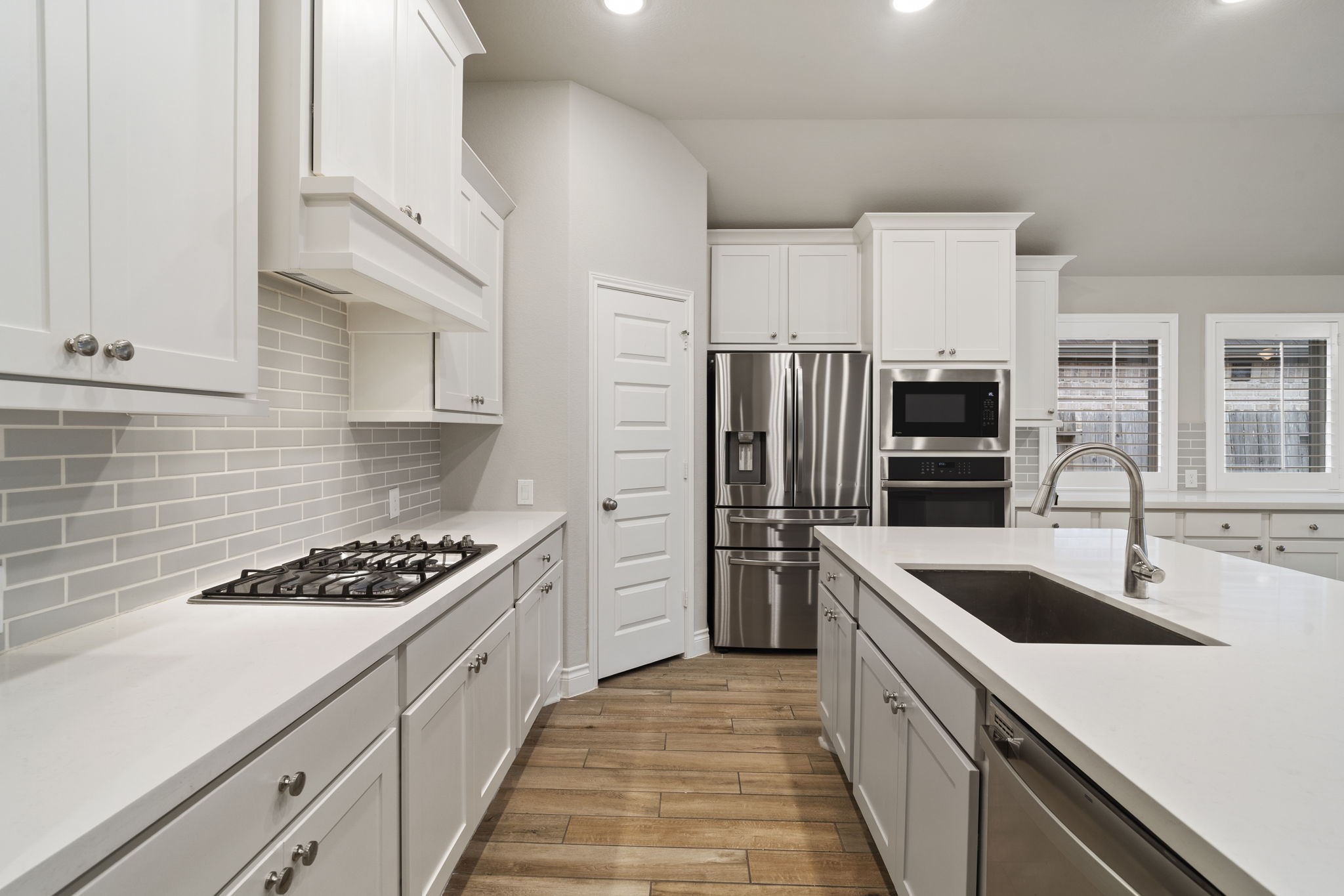 Immaculate and timeless, the kitchen pairs pristine white cabinetry and quartz countertops with soft gray subway tile for a fresh, sophisticated look that never goes out of style. Immaculate and timeless, the kitchen pairs pristine white cabinetry and quartz countertops with soft gray subway tile for a fresh, sophisticated look that never goes out of style.