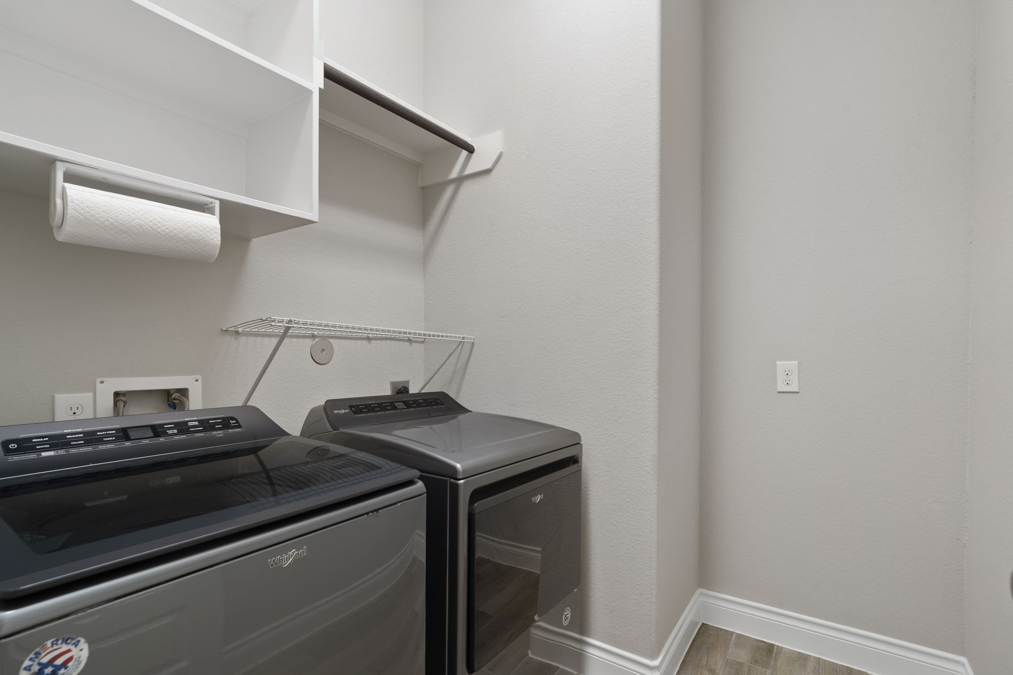 In-home laundry room featuring storage shelving and a hanging rack. Washer and dryer are included in the sale.