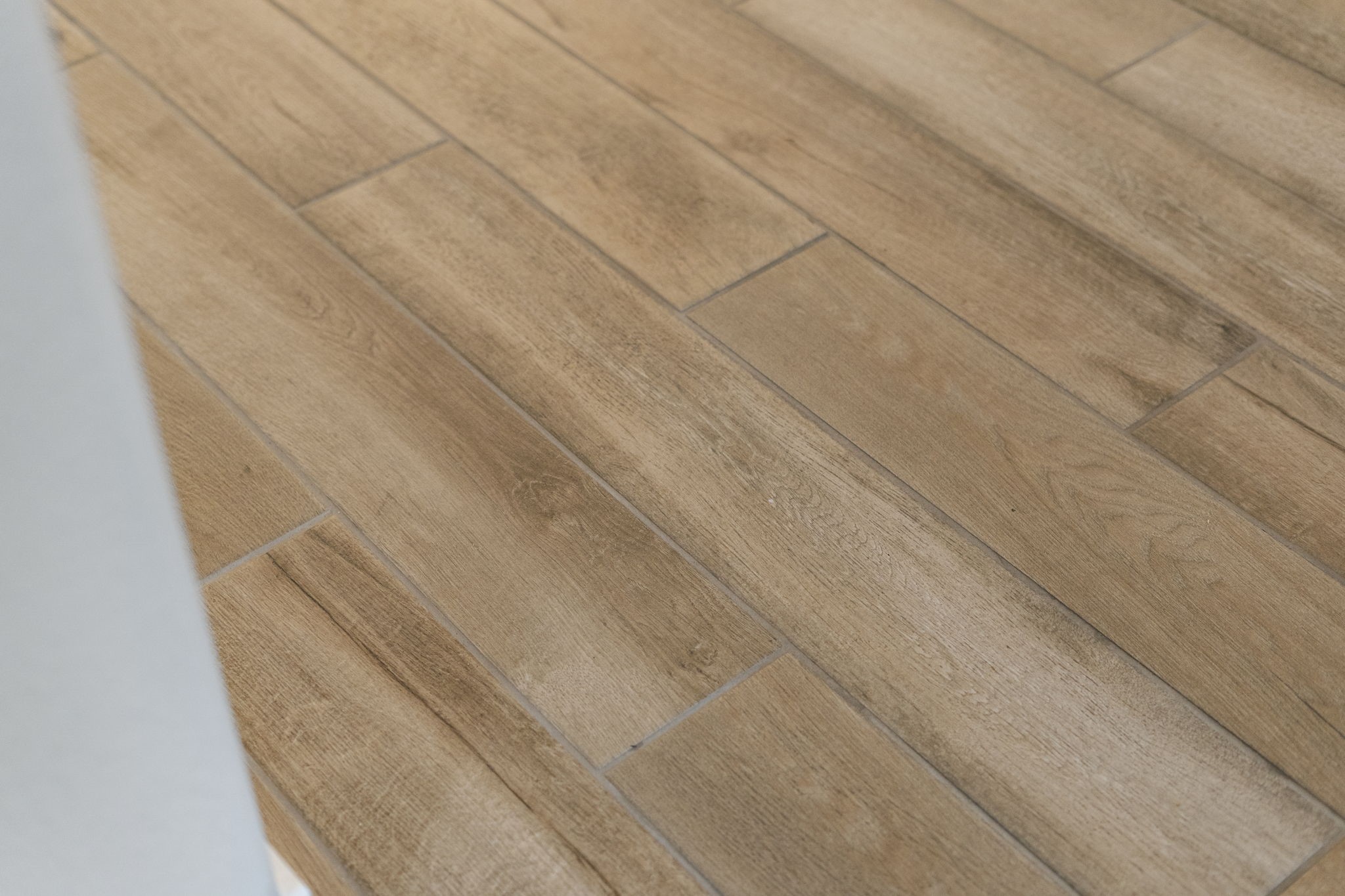 Light wood-look tile flooring offers warmth, durability, and easy maintenance throughout the main living areas.