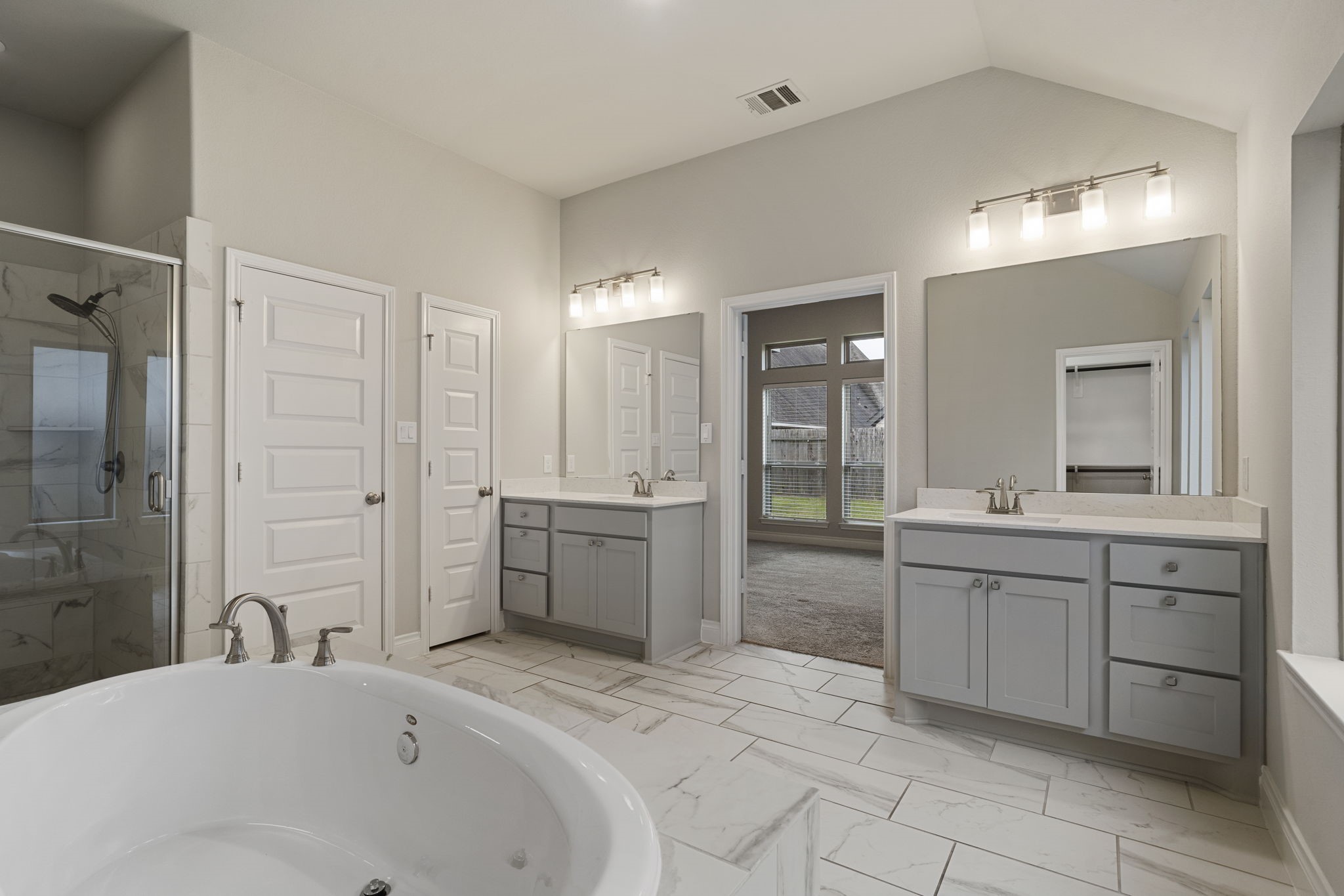 The luxurious owner's bath features dual vanities, a garden tub, a separate glass-enclosed shower, and TWO spacious walk-in closets.