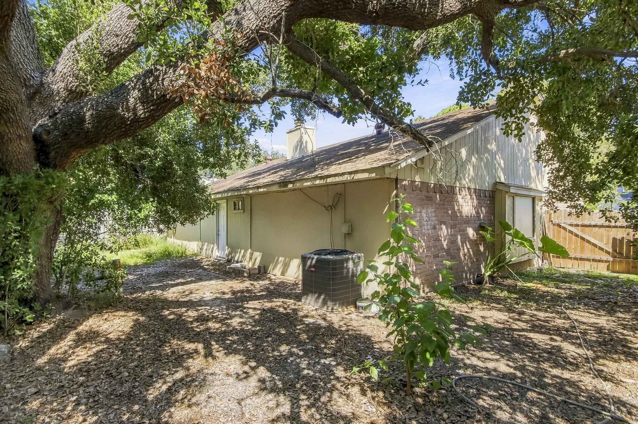 Side view of the home featuring mature trees providing plenty of shade and access to the backyard.