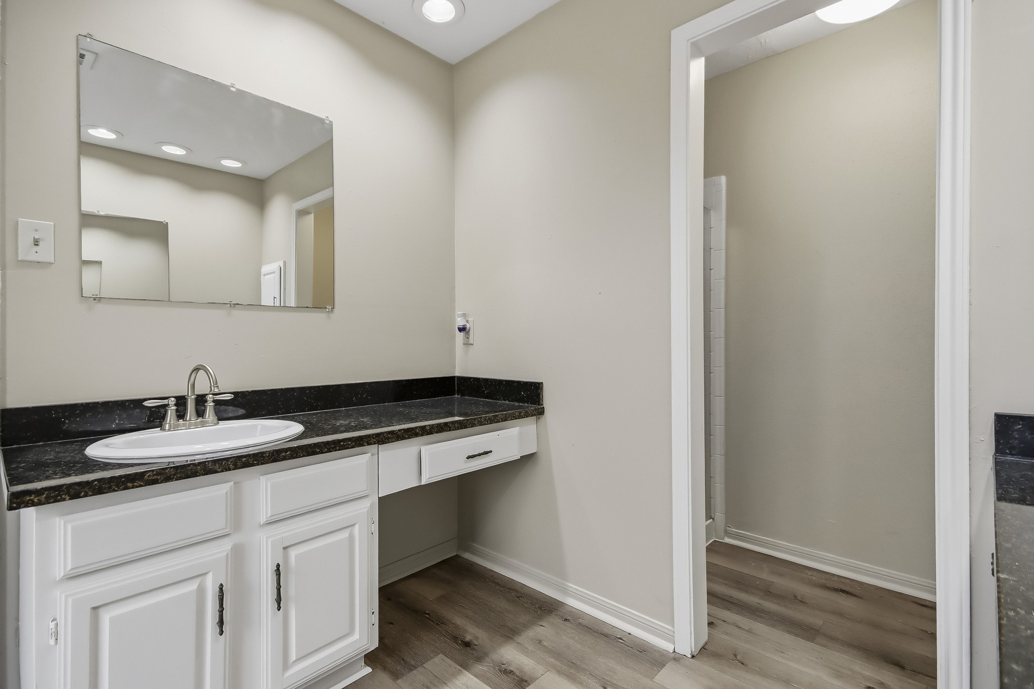 Another view of the primary ensuite bathroom, featuring a vanity with additional counter space and access to the stand-up shower.