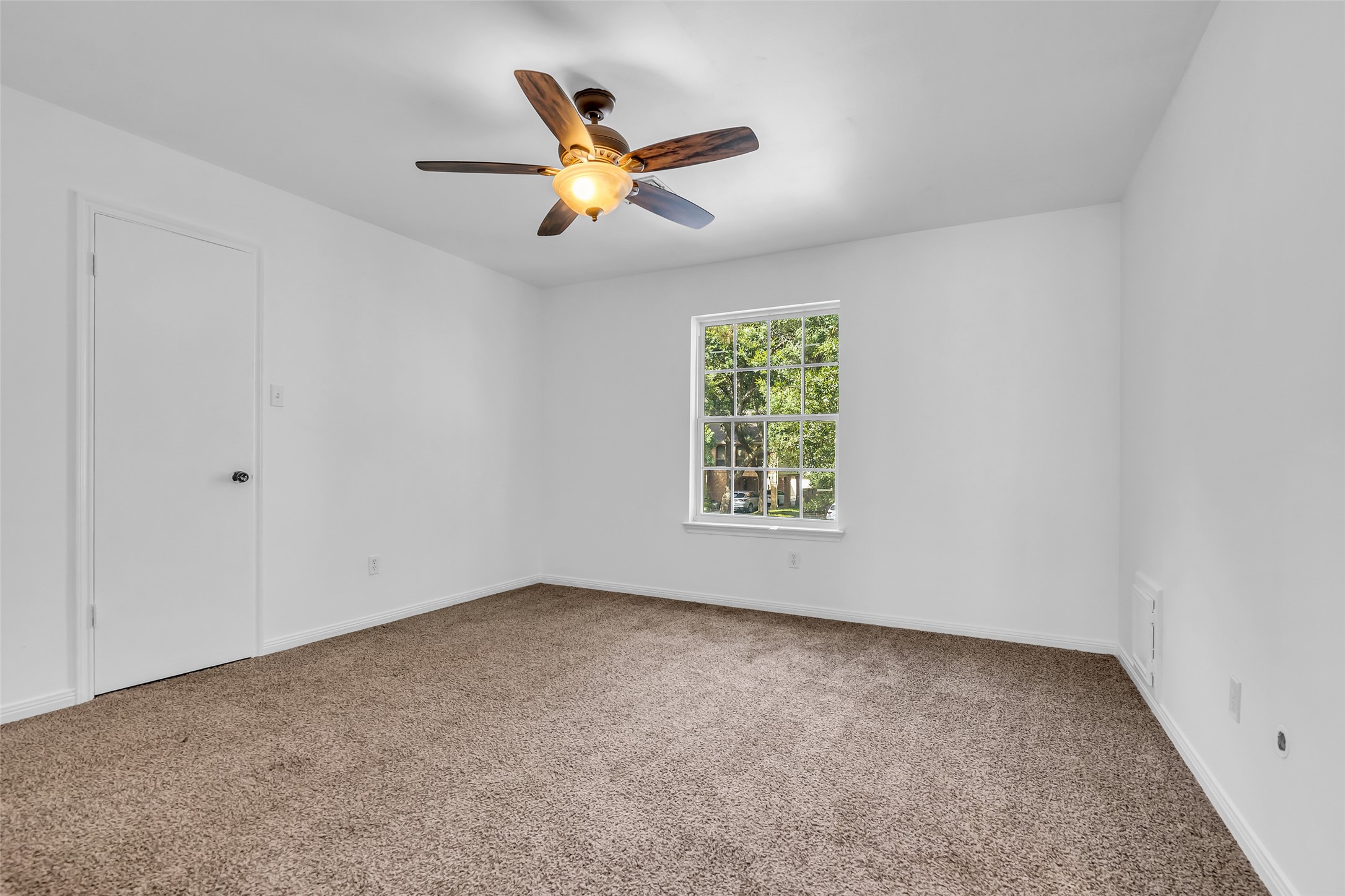 Another bedroom on the second floor overlooking the front lawn, featuring carpeted flooring and a ceiling fan, ready to be styled to suit your personal taste.