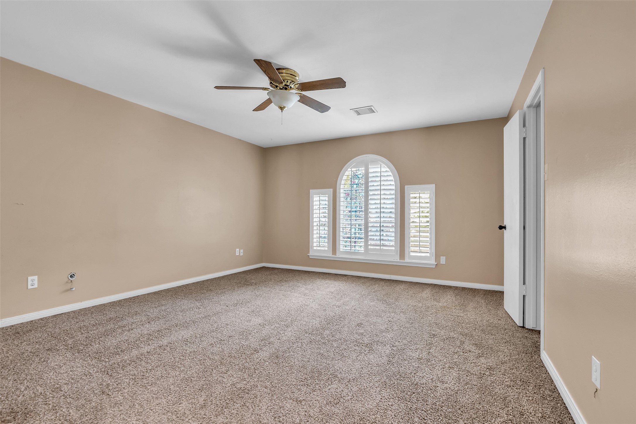 Carpeted bedroom on the second floor with windows overlooking the front lawn, complemented by a ceiling fan to enhance airflow and comfort.