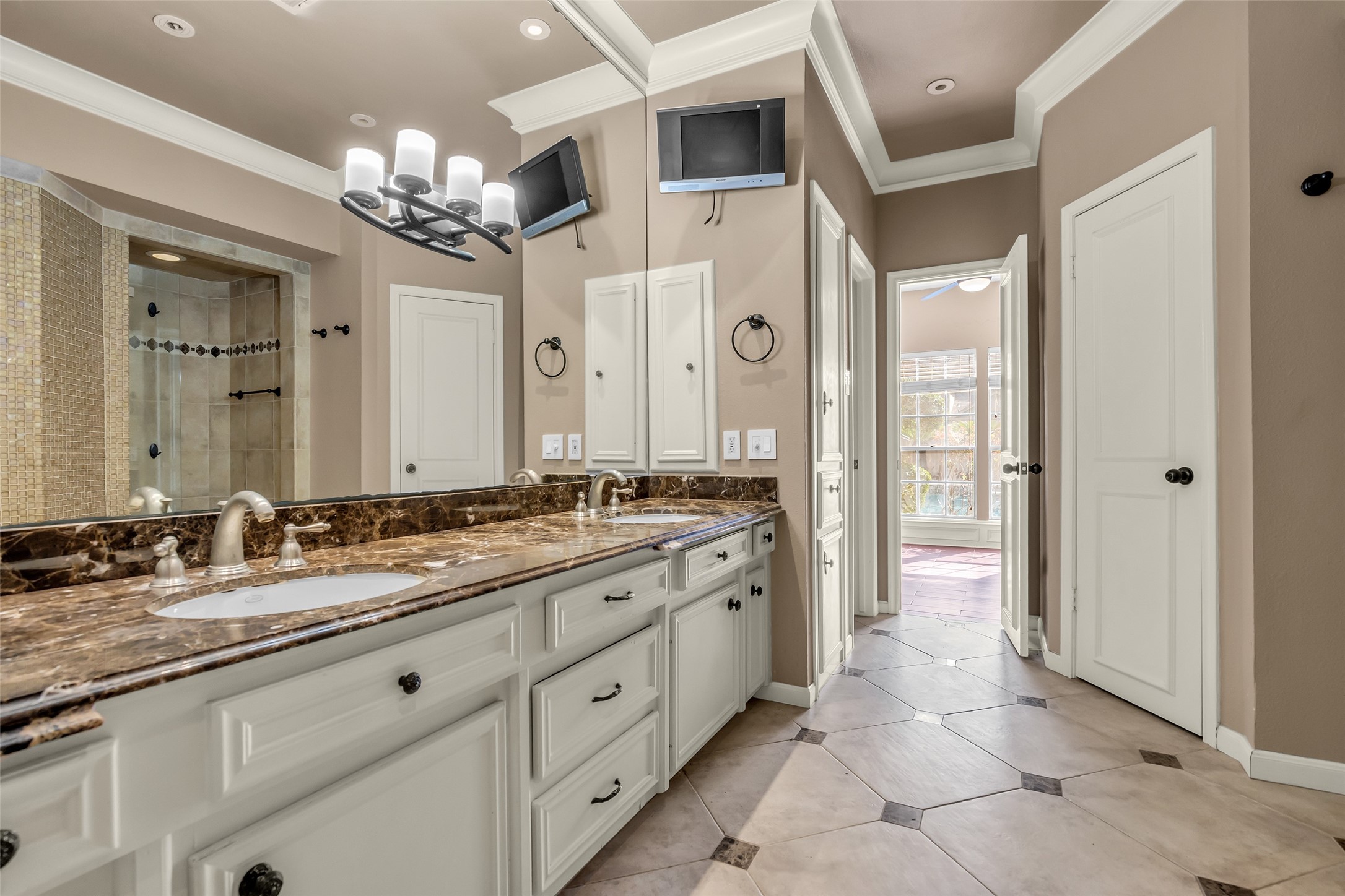 It has dual vanities offering ample counter space and storage. A large walk-in shower serves as the centerpiece, enclosed with frameless glass and finished with elegant tilework for a clean, upscale look.