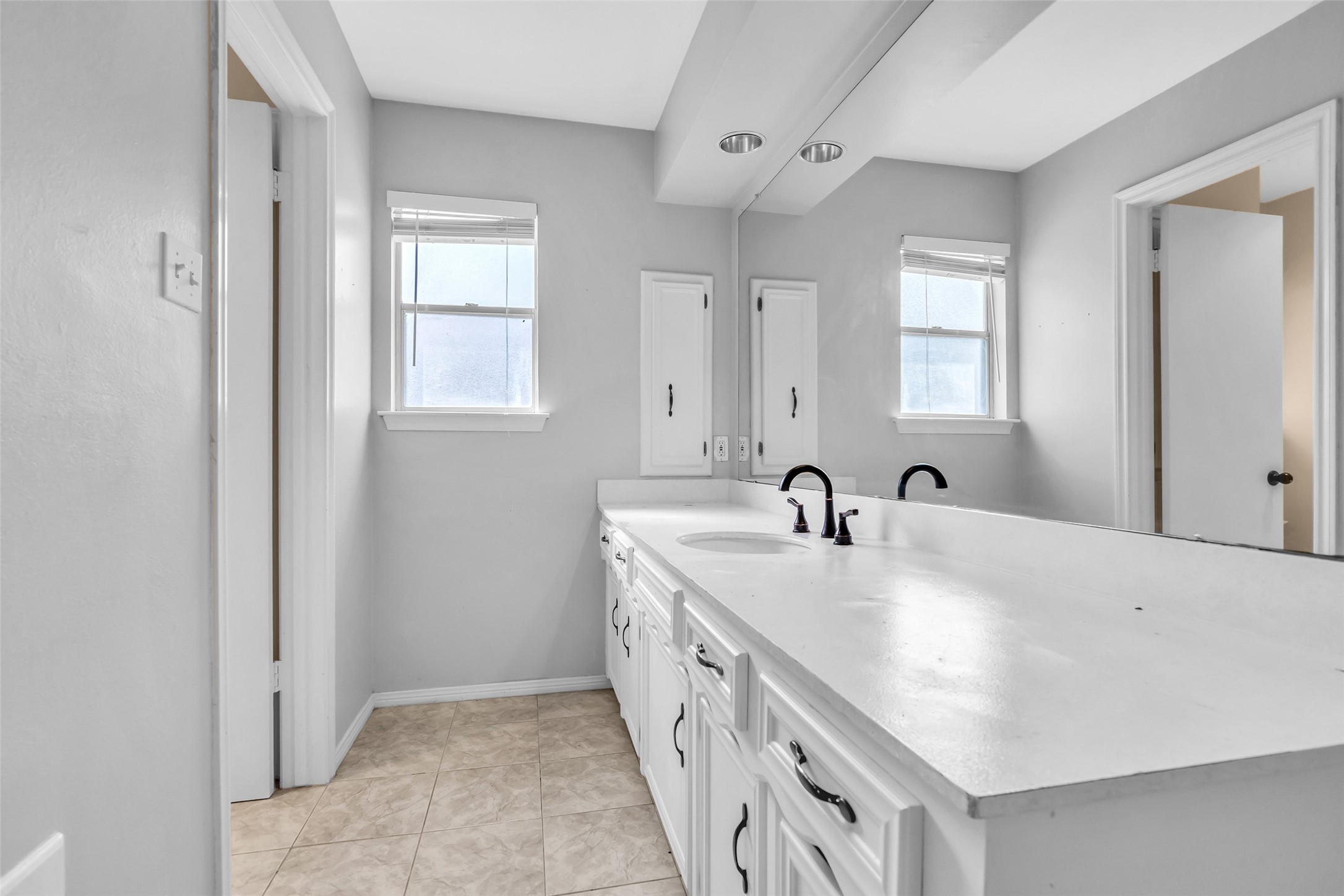 En suite bathroom featuring a large vanity mirror and a tub-and-shower combination for everyday comfort and convenience.