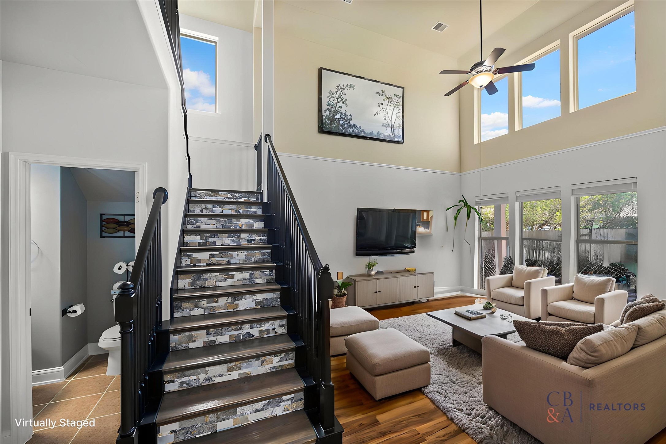 Modern staircase design providing access to the second floor. Living room furniture virtually staged.
