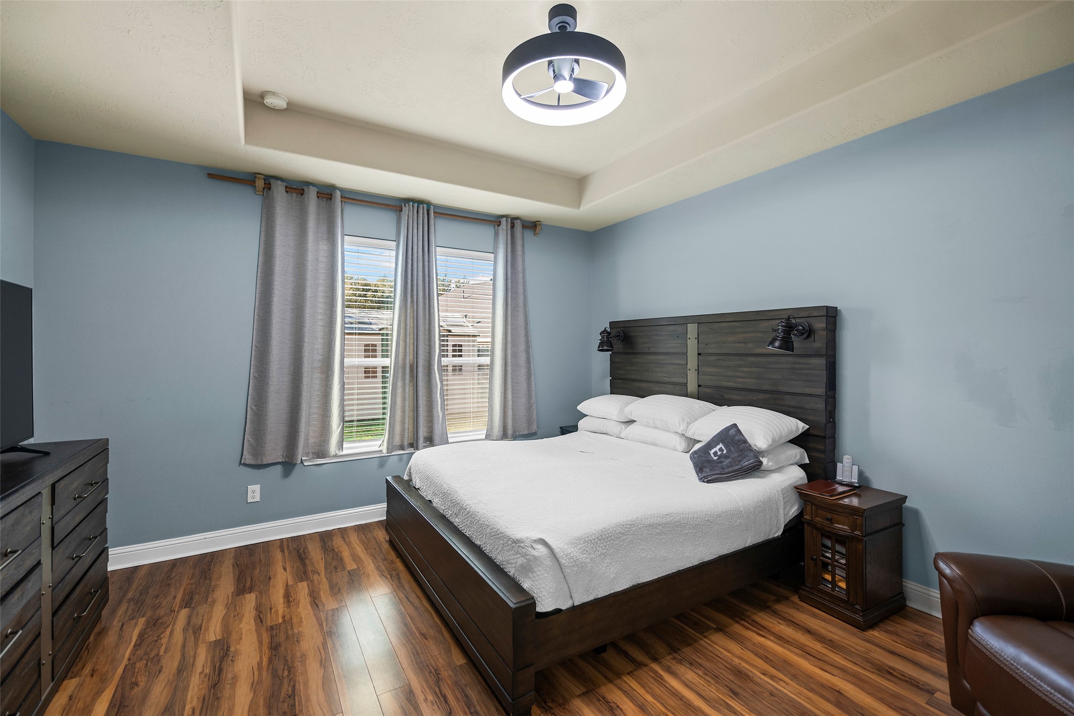 The primary bedroom is located on the first floor and features elegant flooring paired with a modern light fixture.