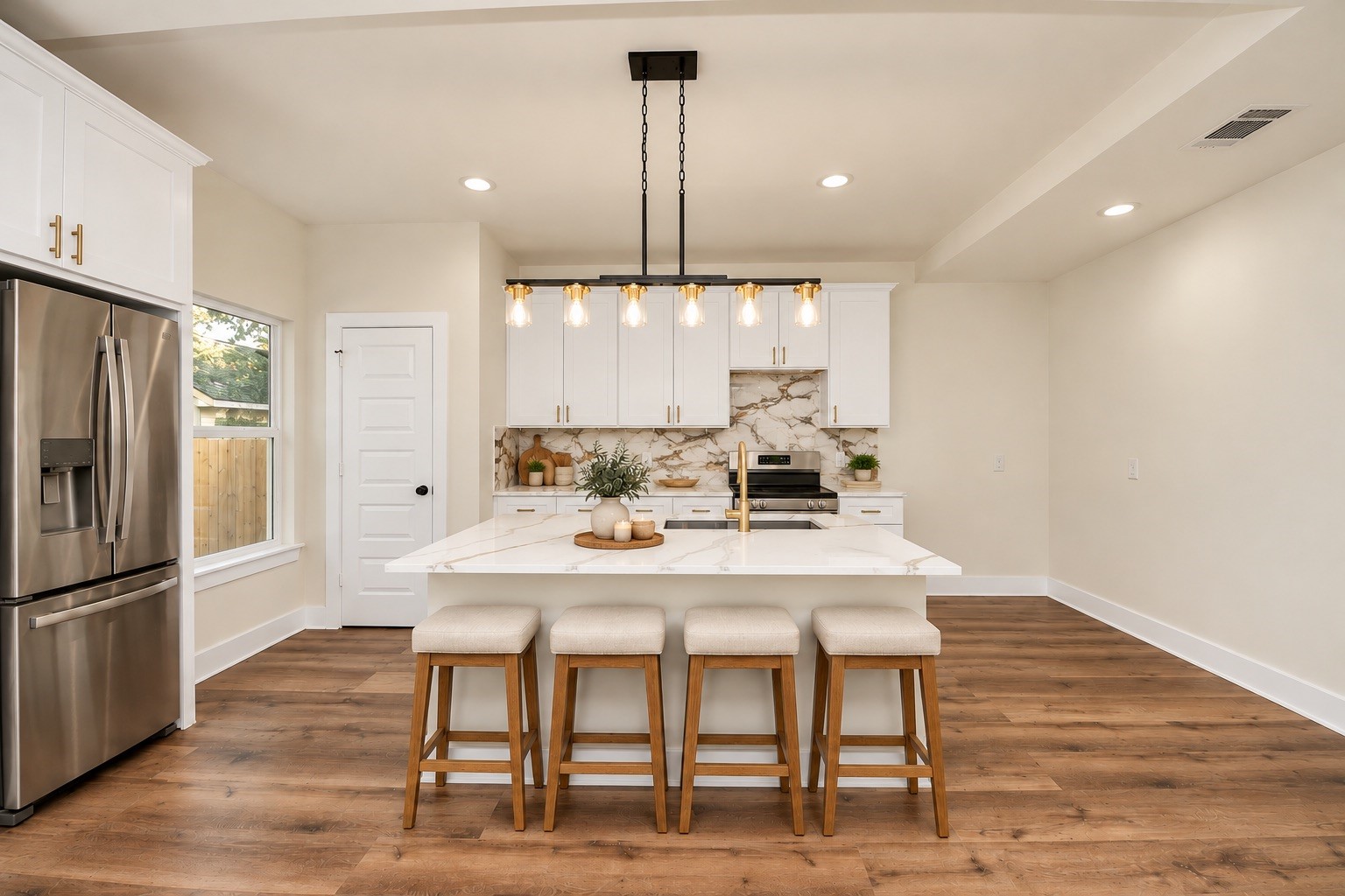 Beautifully appointed kitchen featuring quartz countertops, white soft-close cabinetry, stainless steel appliances, stylish pendant lighting & a generously sized center island with bar seating.