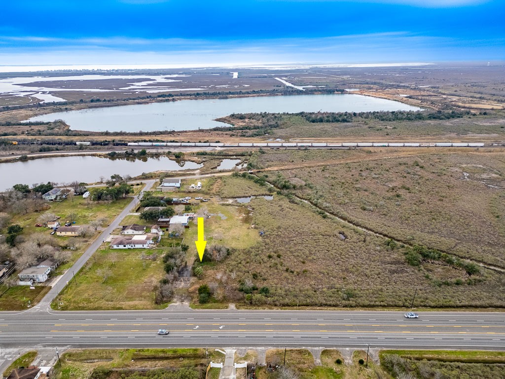 Wide aerial view with arrow identifying the subject property directly along Highway 6 with surrounding wetlands, waterways, and rail corridor visible. Wide aerial view with arrow identifying the subject property directly along Highway 6 with surrounding wetlands, waterways, and rail corridor visible.