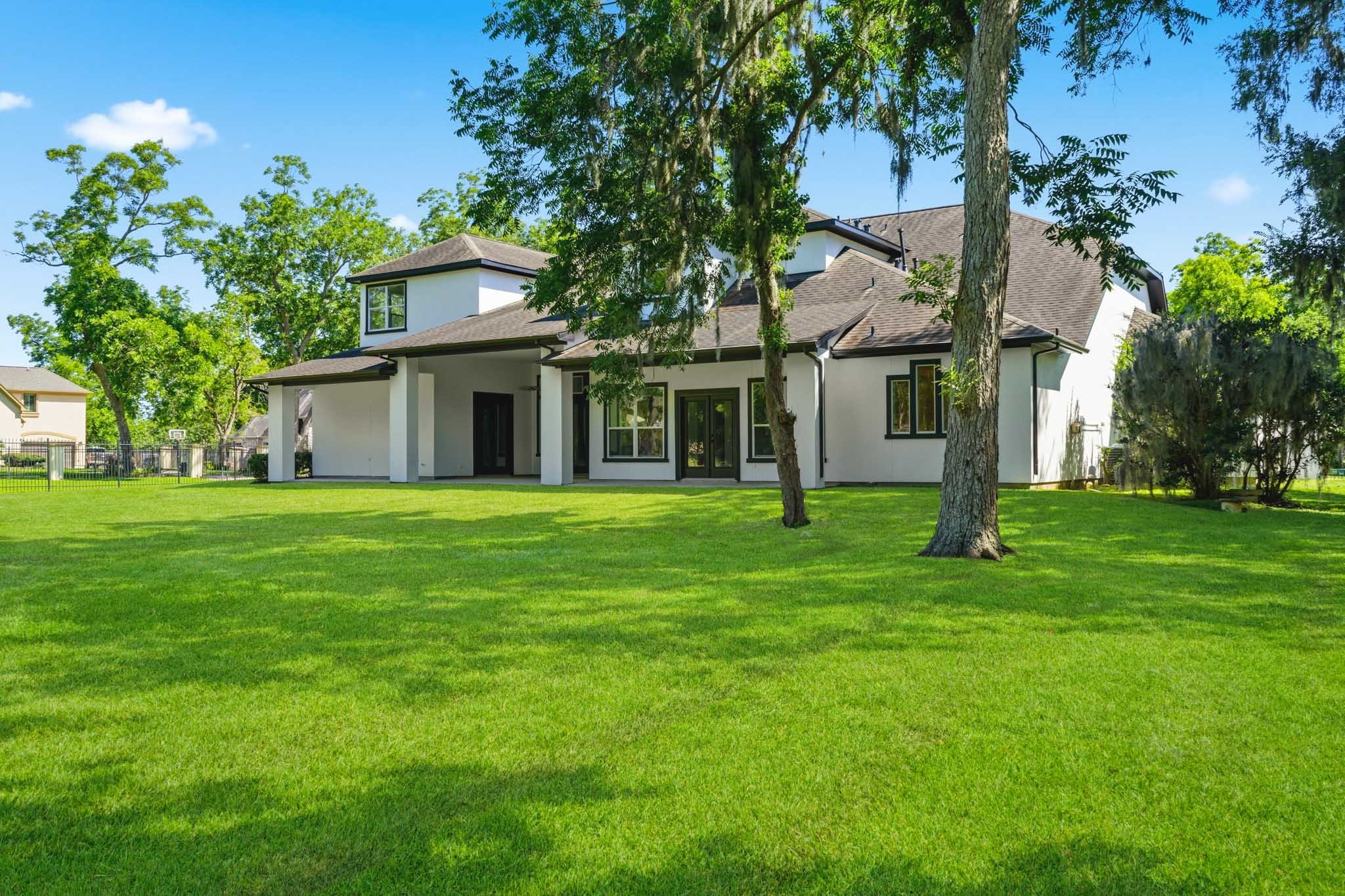 Rear exterior showcasing the oversized backyard and covered outdoor living space.