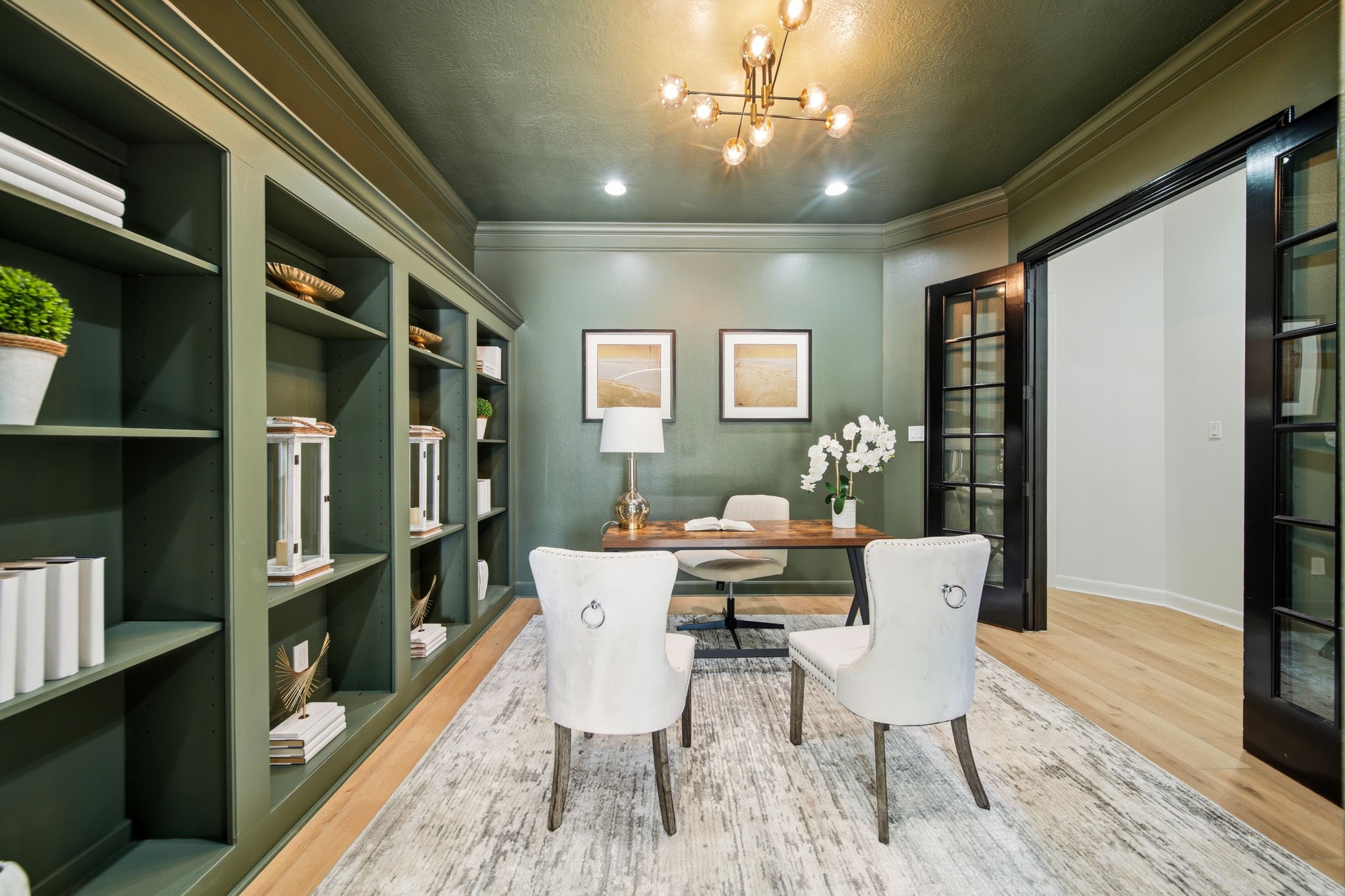 Private home office with built-in shelving, French doors, and refined designer touches.