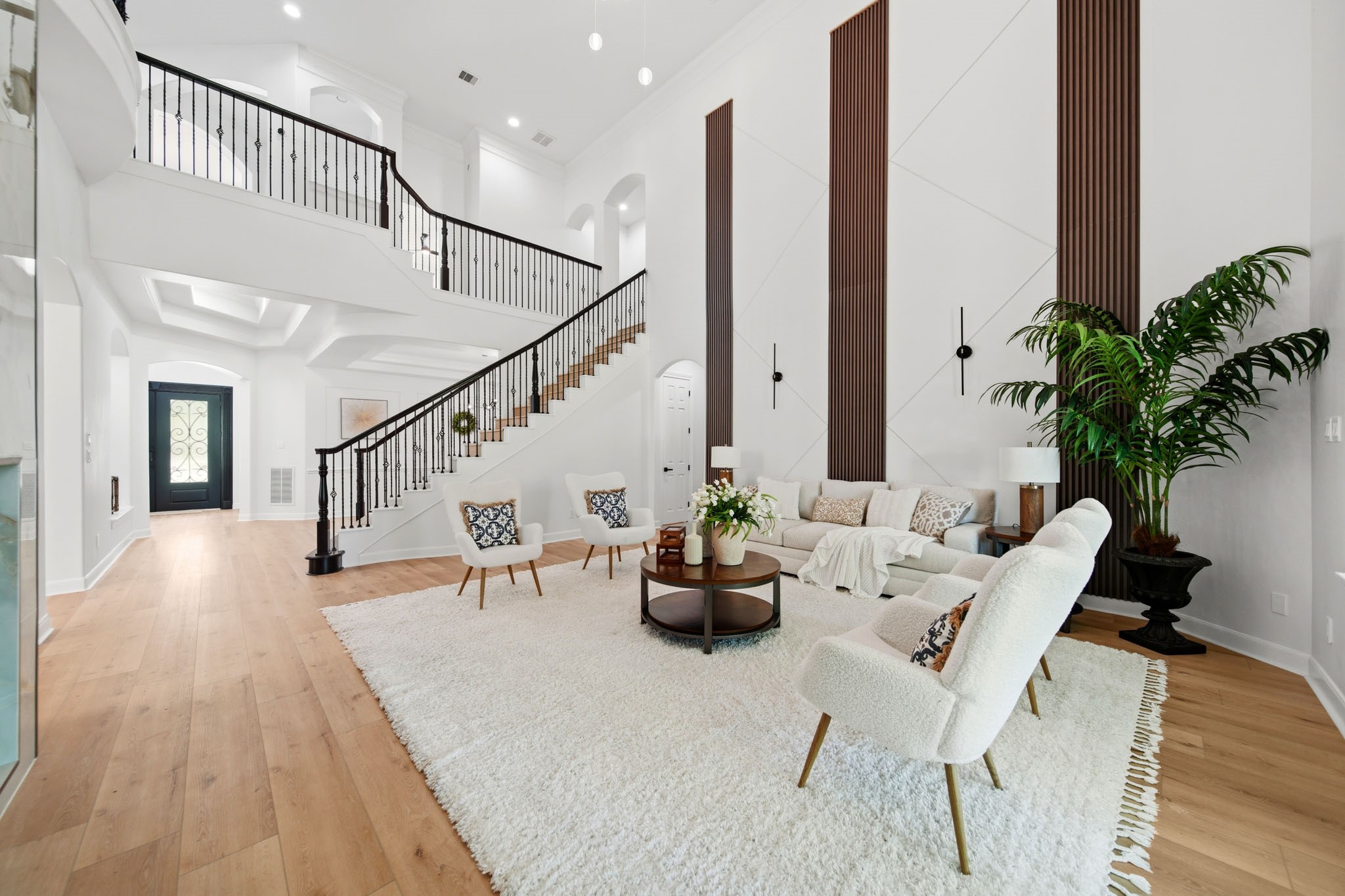 Open-concept living space featuring dramatic ceilings, statement wall accents, and ample lighting