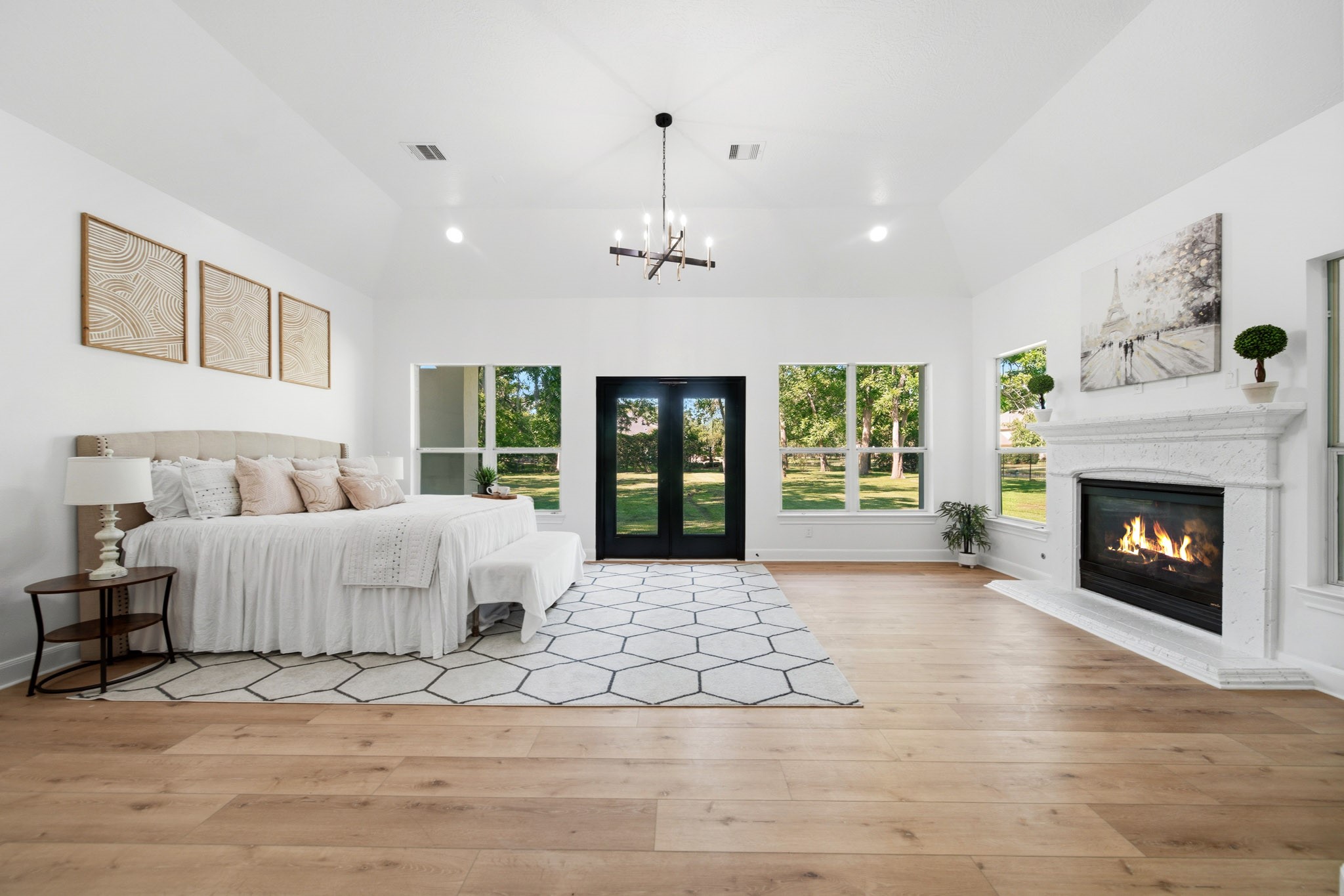 Luxurious primary suite with soaring ceilings, fireplace, and serene backyard views.