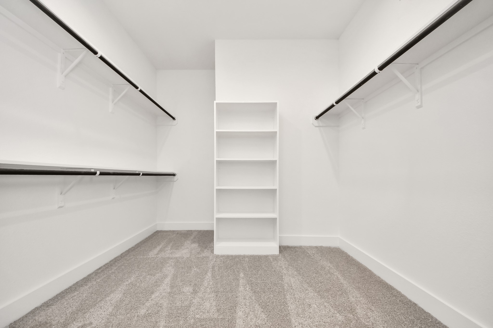 Walk-in closet that epitomizes luxury and practicality. This generously sized space features built-in shelving, offering abundant room for impeccable organization. High ceilings and recessed lighting create a bright and welcoming ambiance. Sample photo of completed home with similar floor plan. Actual colors and selections may vary.