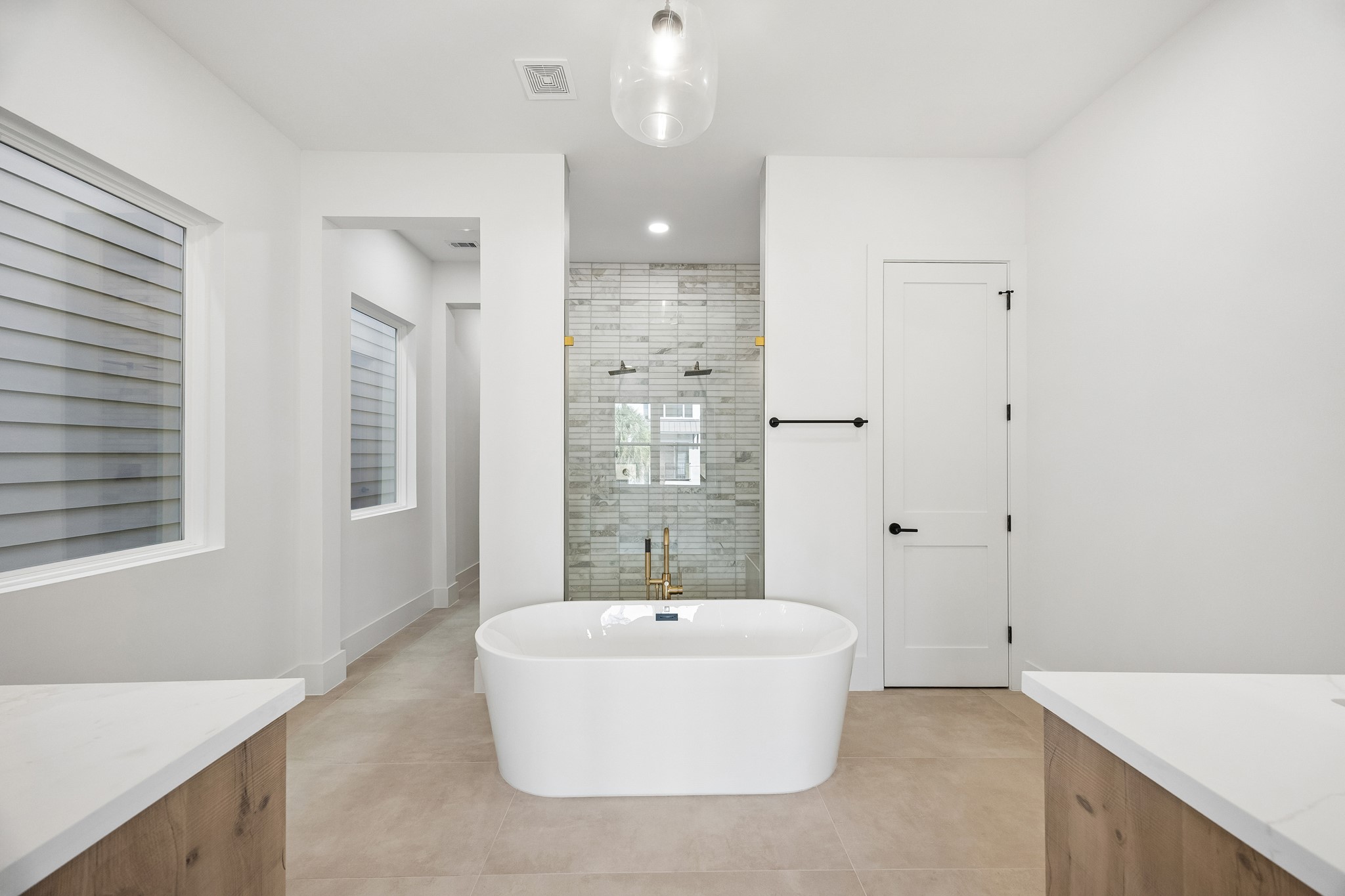 Luxurious primary bath  offers a wood-tone vanity, designer mirror and freestanding tub.