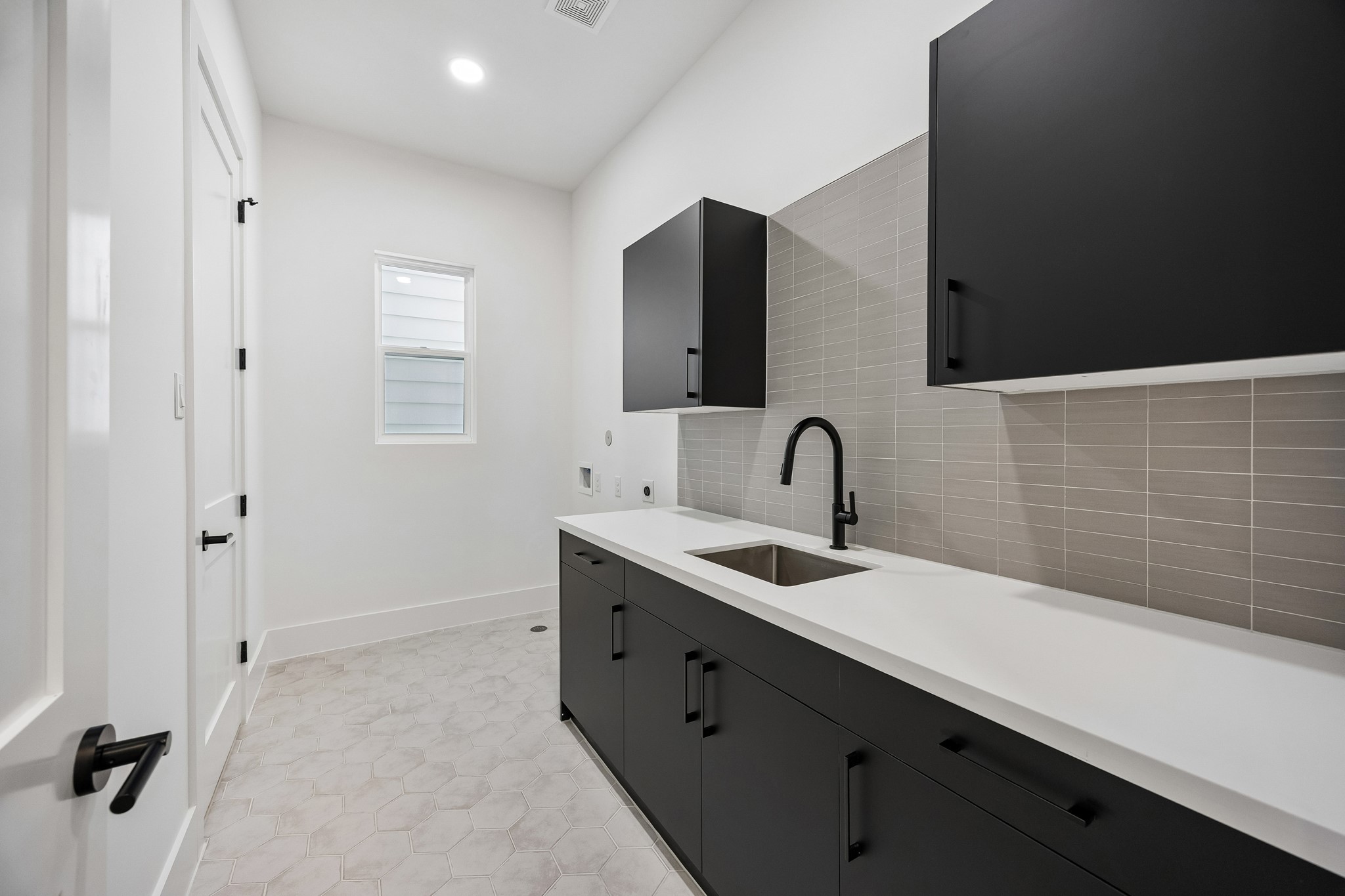 Utility room  features built-in cabinetry, countertop space, an undermount sink and tile backsplash. Dual entry from second floor hallway and primary closet.