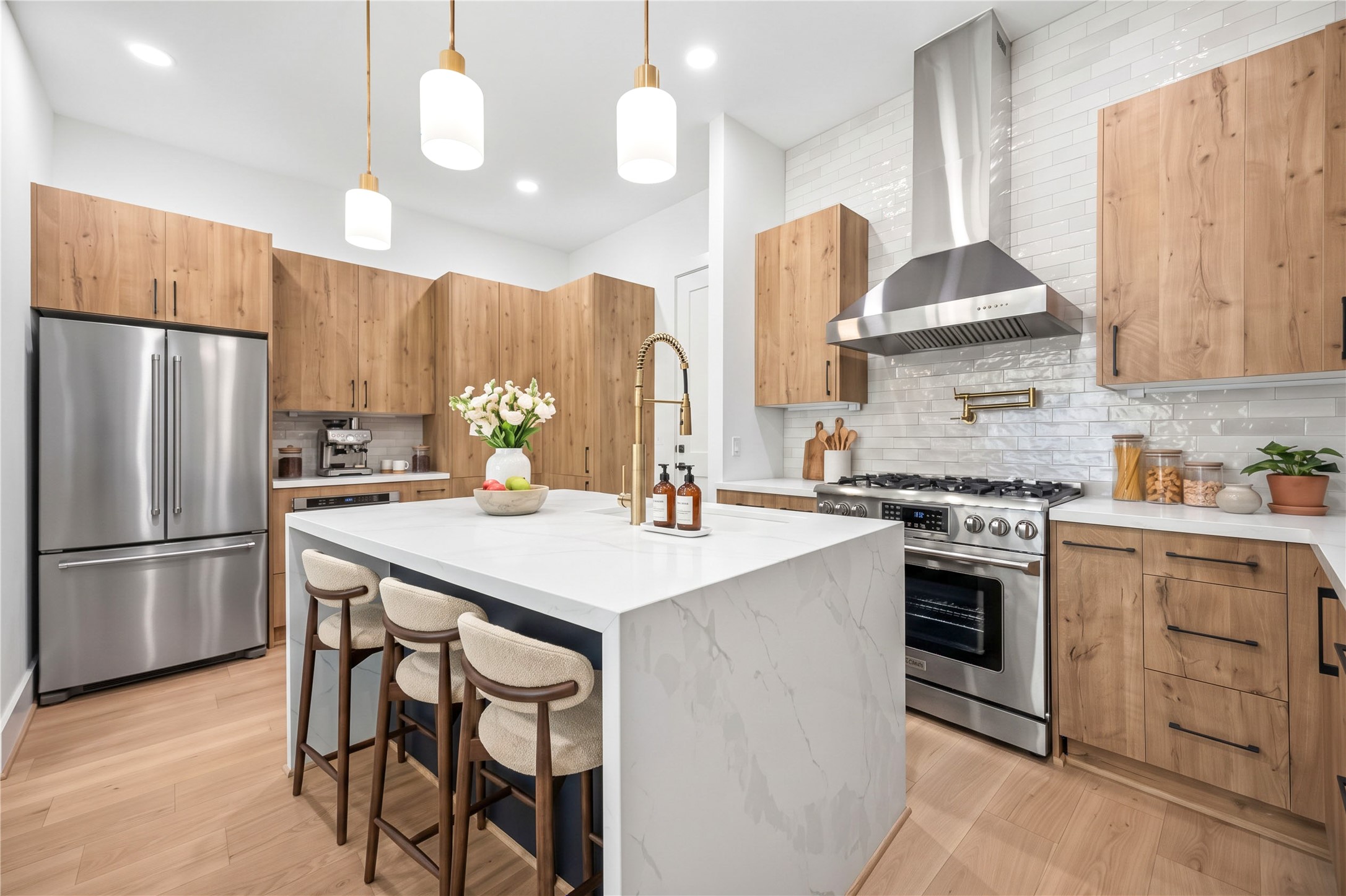 Kitchen  expansive waterfall island provides additional prep and seating space, complemented by a stainless steel gas range and pot filler. (virtual staging)