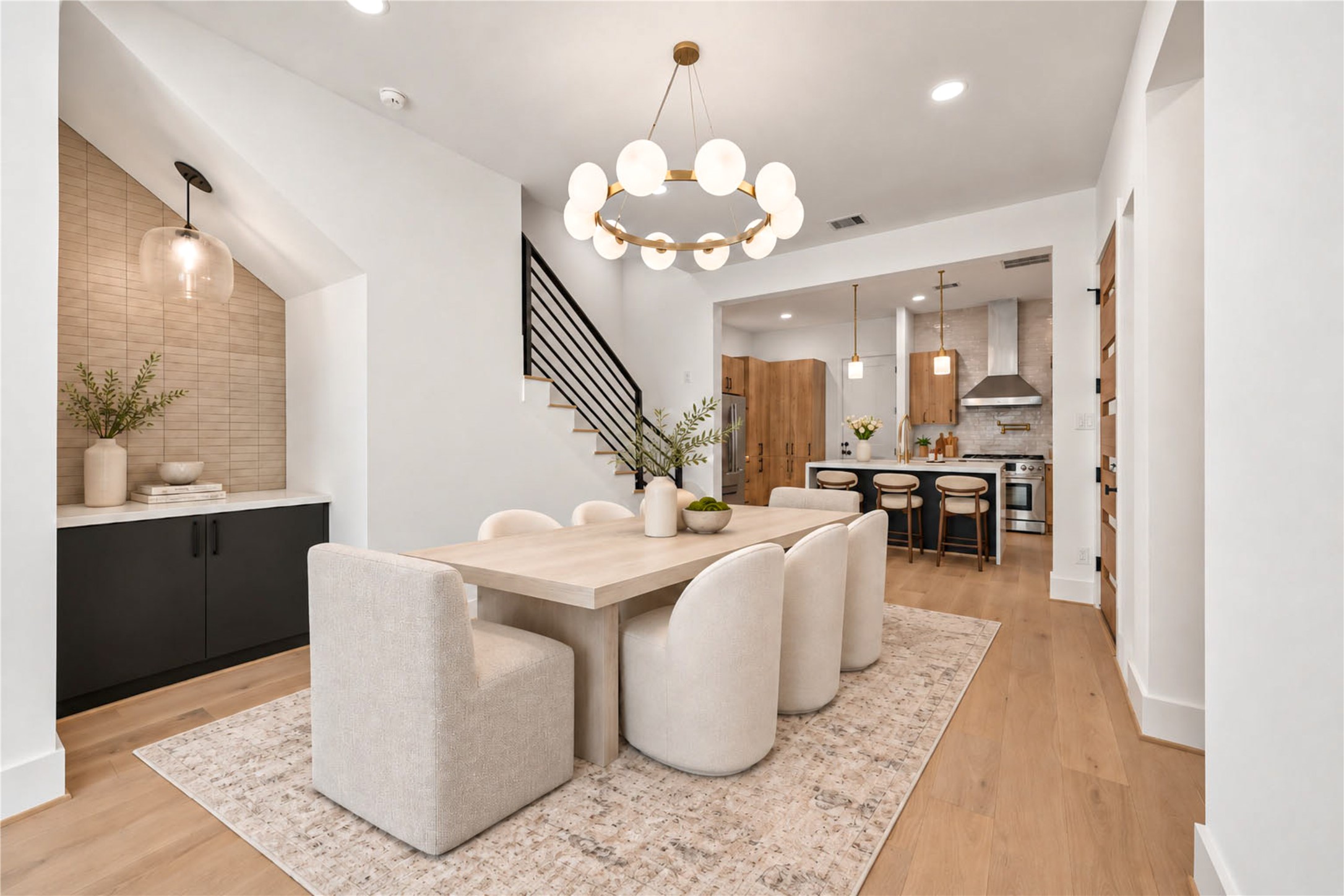 Open first floor  features a modern globe chandelier, staircase with black metal railing and views of the backyard. (virtual staging)