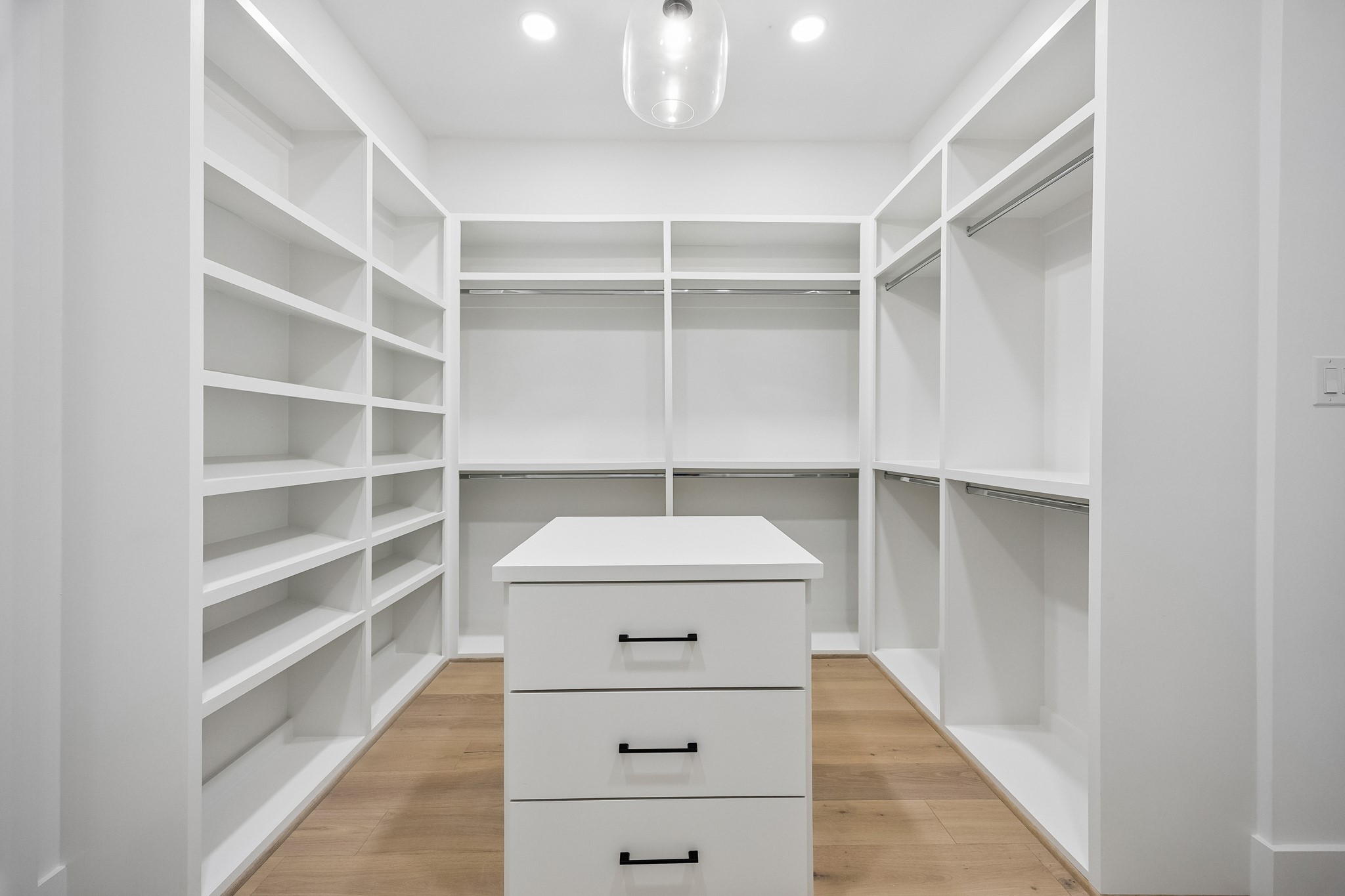 Primary walk-in closet  features extensive custom built-ins, shelving, drawers and a center storage island.