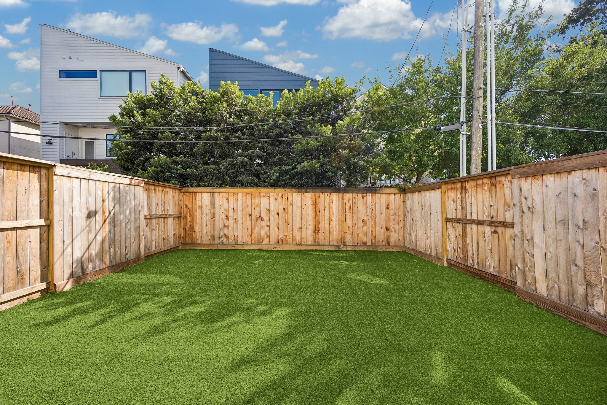 Backyard offers privacy, enclosed by wood fencing with mature trees beyond.