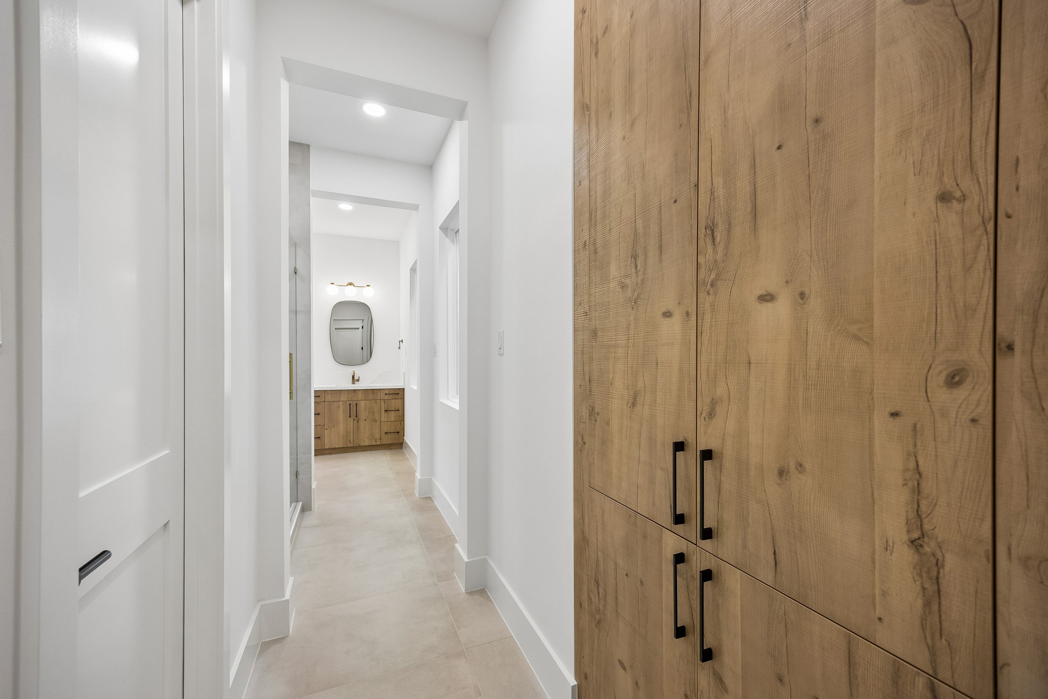 Primary suite hallway  offers built-in linen cabinetry.
