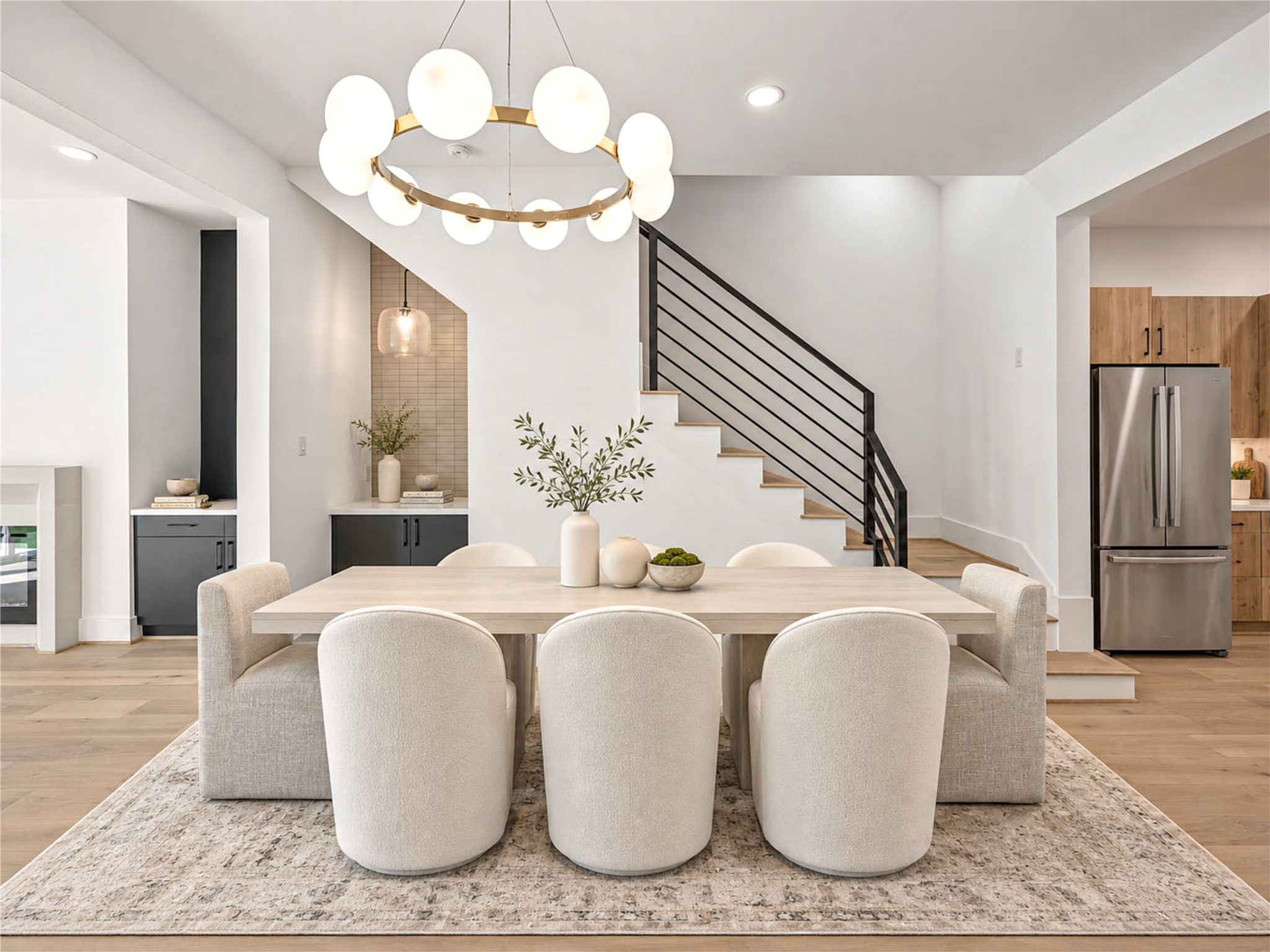 Dining area  features a sculptural chandelier, a built-in dry bar and seamless flow into the kitchen. (virtual staging)