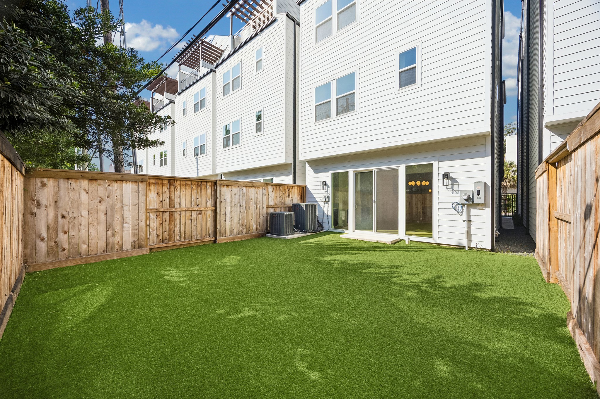 Private backyard  offers low-maintenance turf enclosed by wood fencing, ideal for outdoor living and entertaining.
