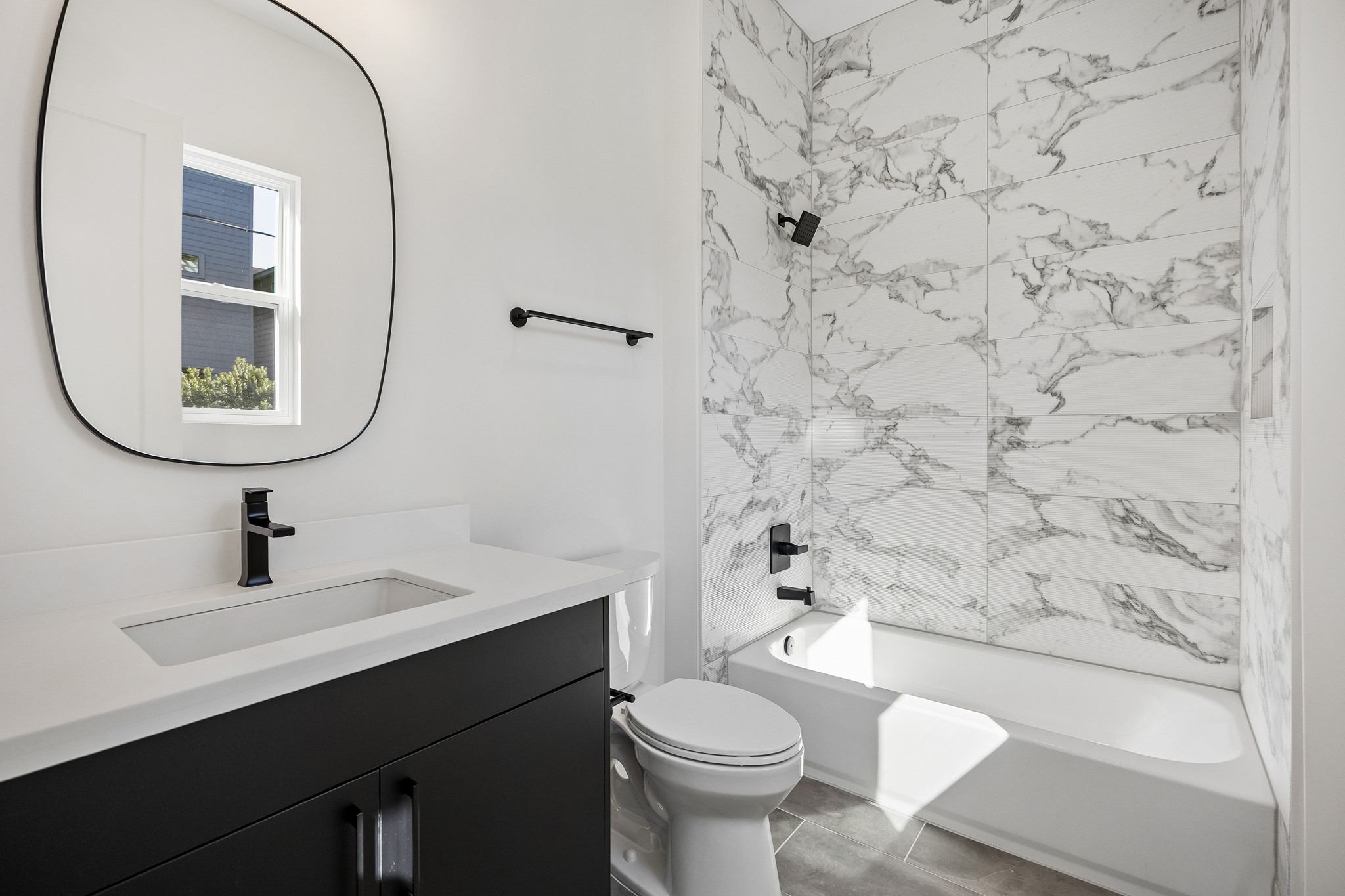 Bath #3  offers a dark vanity, designer mirror and tub/shower combo.
