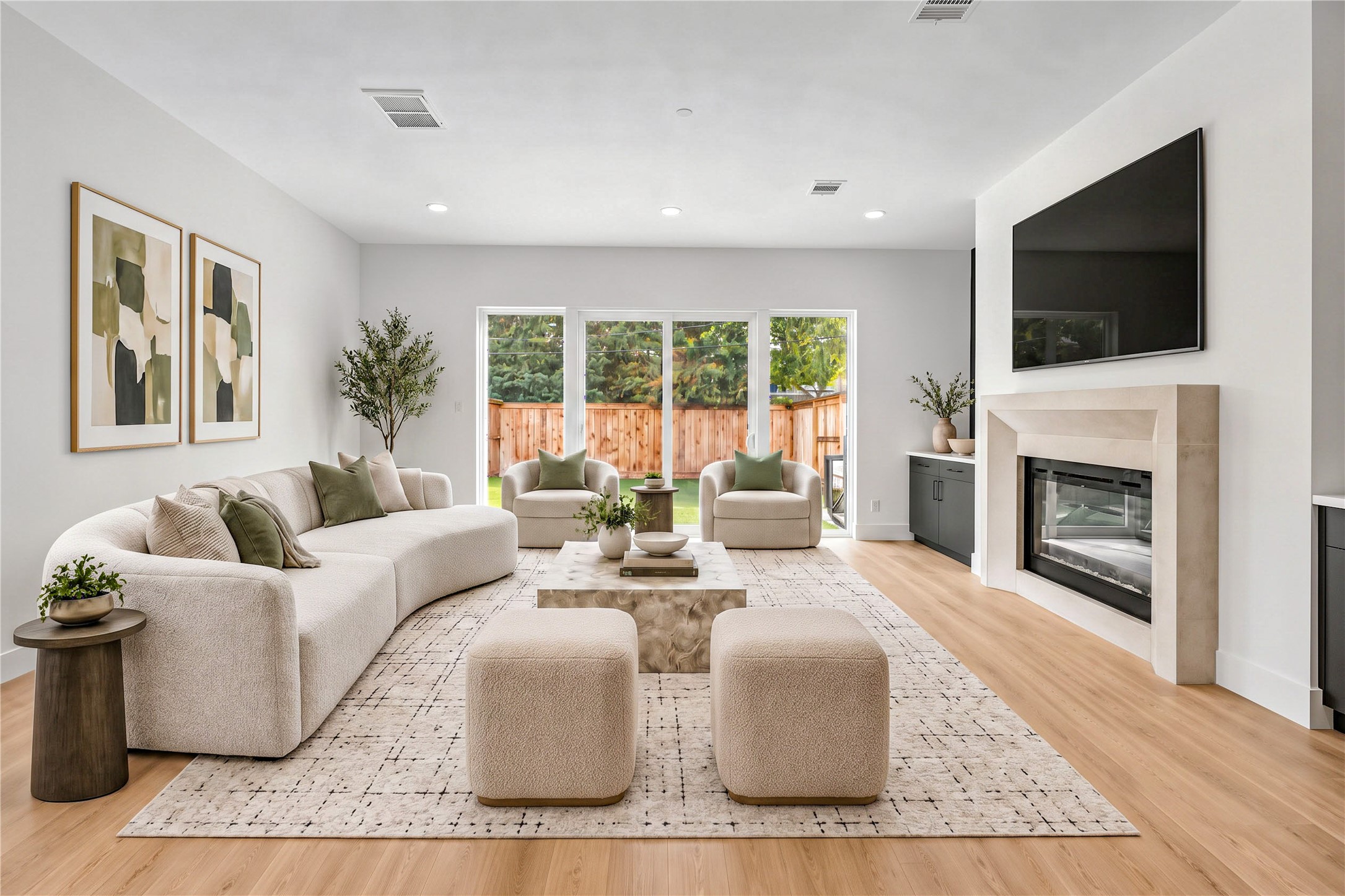 Living room  features a sleek linear fireplace, built-in cabinetry, a statement accent wall and wood flooring. (virtual staging) Another view of the spacious living room with sliding glass doors overlooking the backyard. (virtual staging)