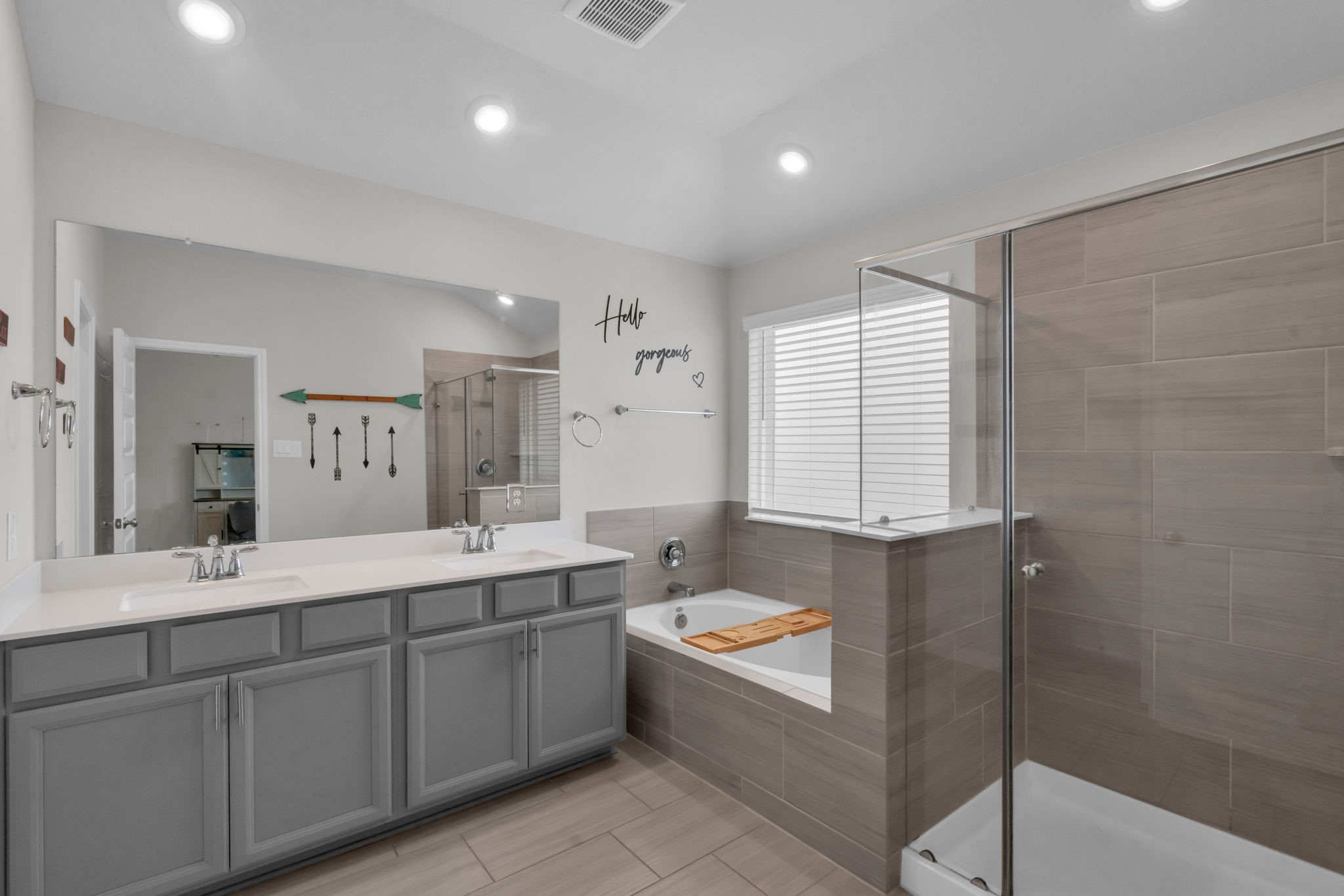 Primary bathroom features dual sinks, a relaxing soaking tub, and a glass-standing shower.