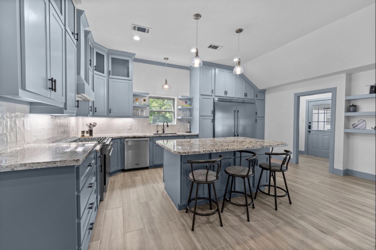 Main-house kitchen with a large island, breakfast-bar seating, pendant lighting, and abundant cabinetry.