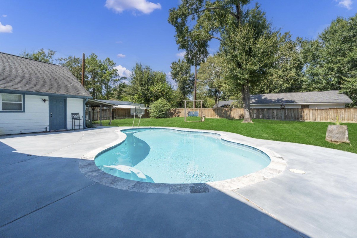 Pool view looking toward the fenced backyard and mature trees.