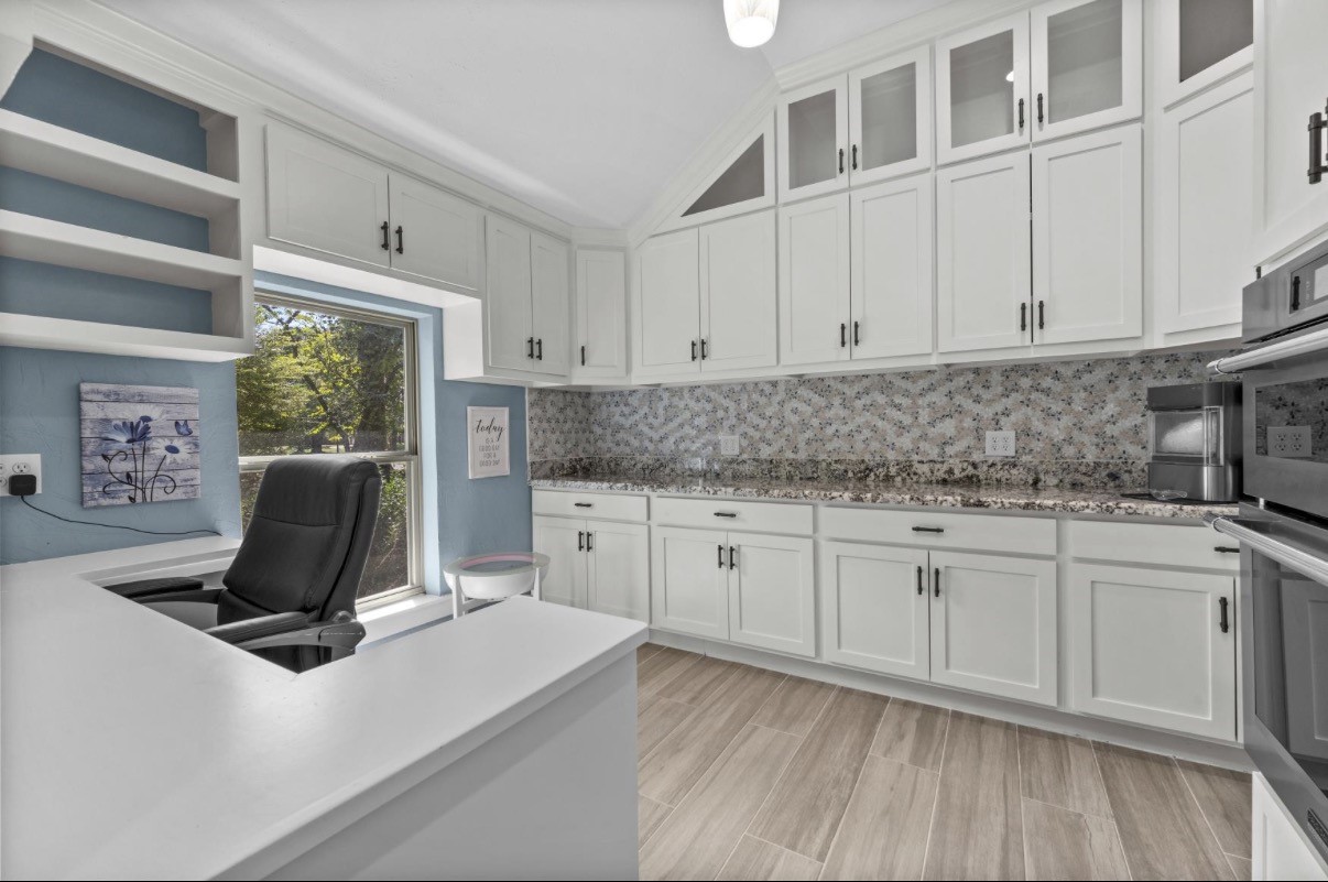 A flexible workspace with extensive built-in cabinetry and a window overlooking the outdoors.