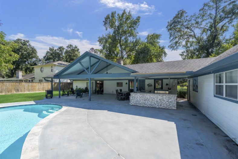 Poolside view of the covered patio and outdoor kitchen.