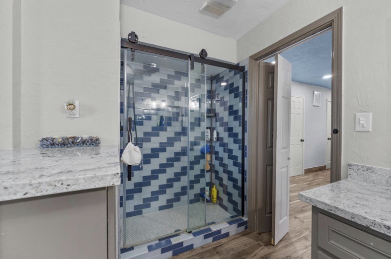 Glass-enclosed shower with distinctive blue tile detailing.