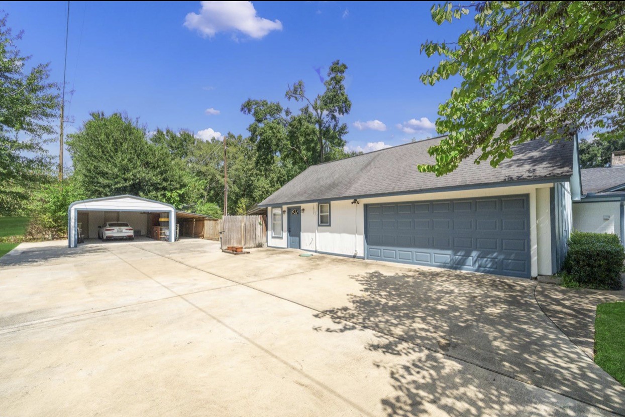 Wide driveway with access to the garage and covered parking area.