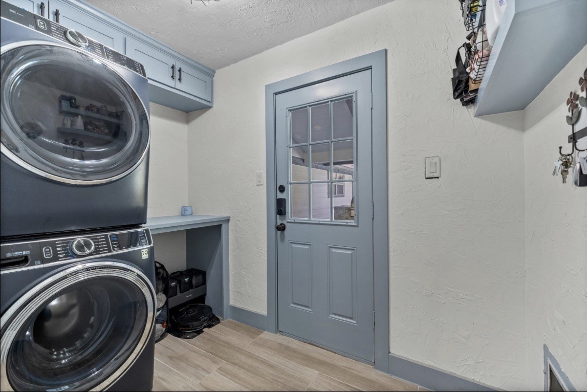 Dedicated laundry room with a stacked washer and dryer, cabinetry, and a folding counter.