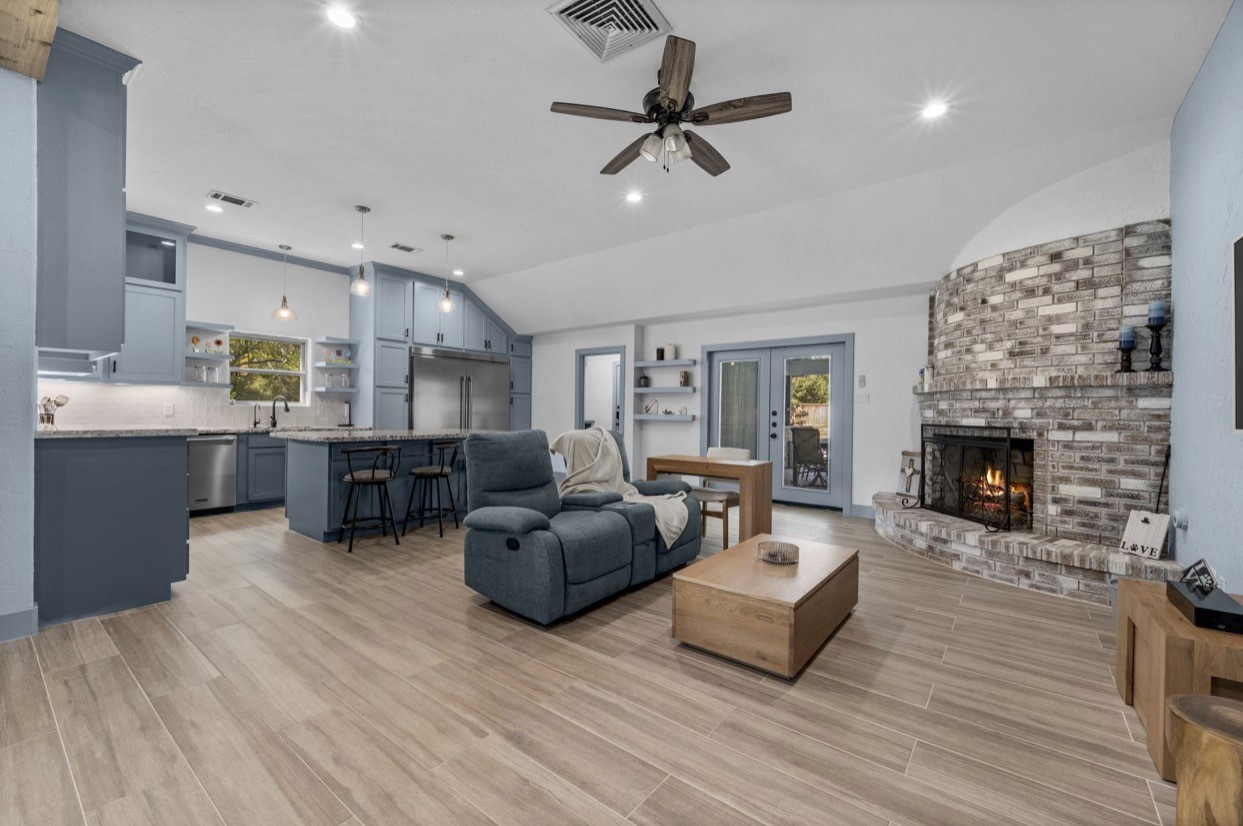 An open layout connects the living room, island kitchen, and outdoor access.