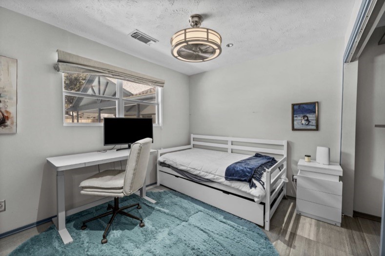 Separate guest-suite bedroom with natural light, closet space, and room for a desk. The suite also includes its own full kitchen, bathroom, and living/dining area.