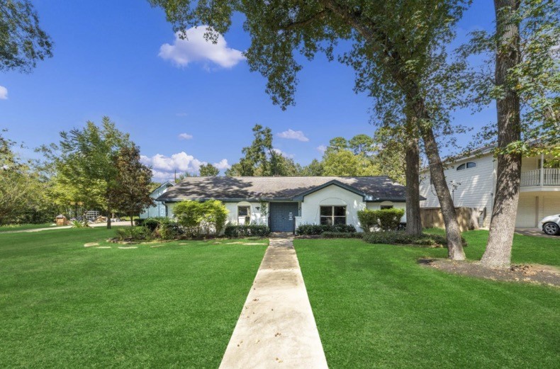 A generous front lawn and mature trees frame the walkway to the home.