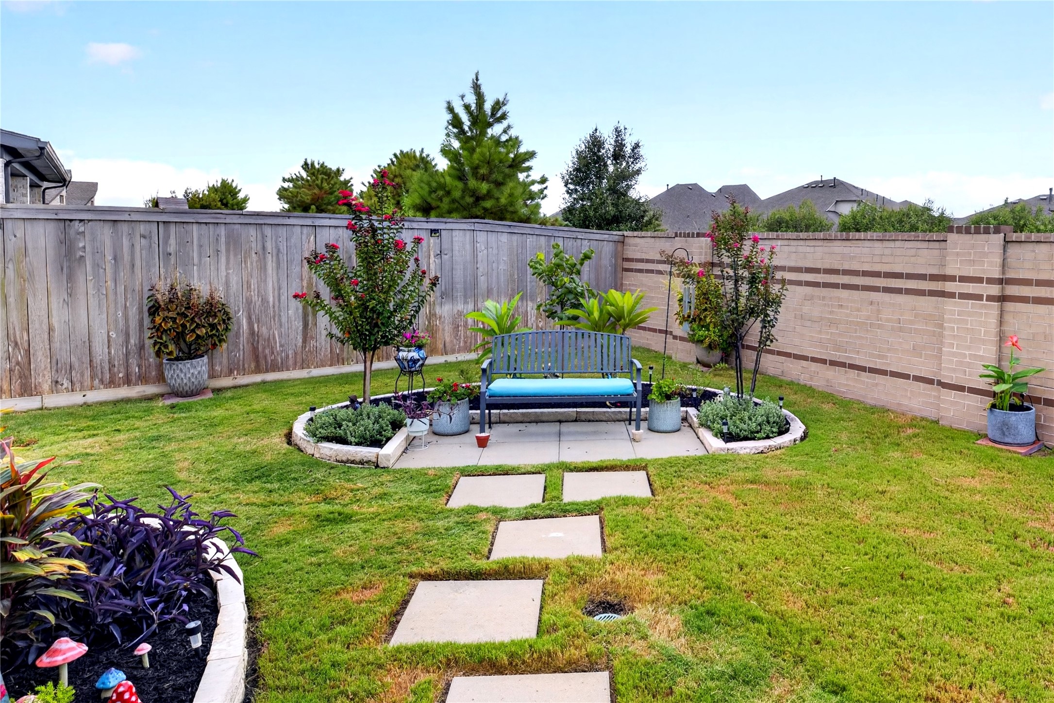 Beautiful landscaped backyard, mature greenery, colorful garden beds and a charming seating area. A stepping stone pathway leads to the private garden retreat, creating a peaceful space for relaxing or entertaining outdoors.