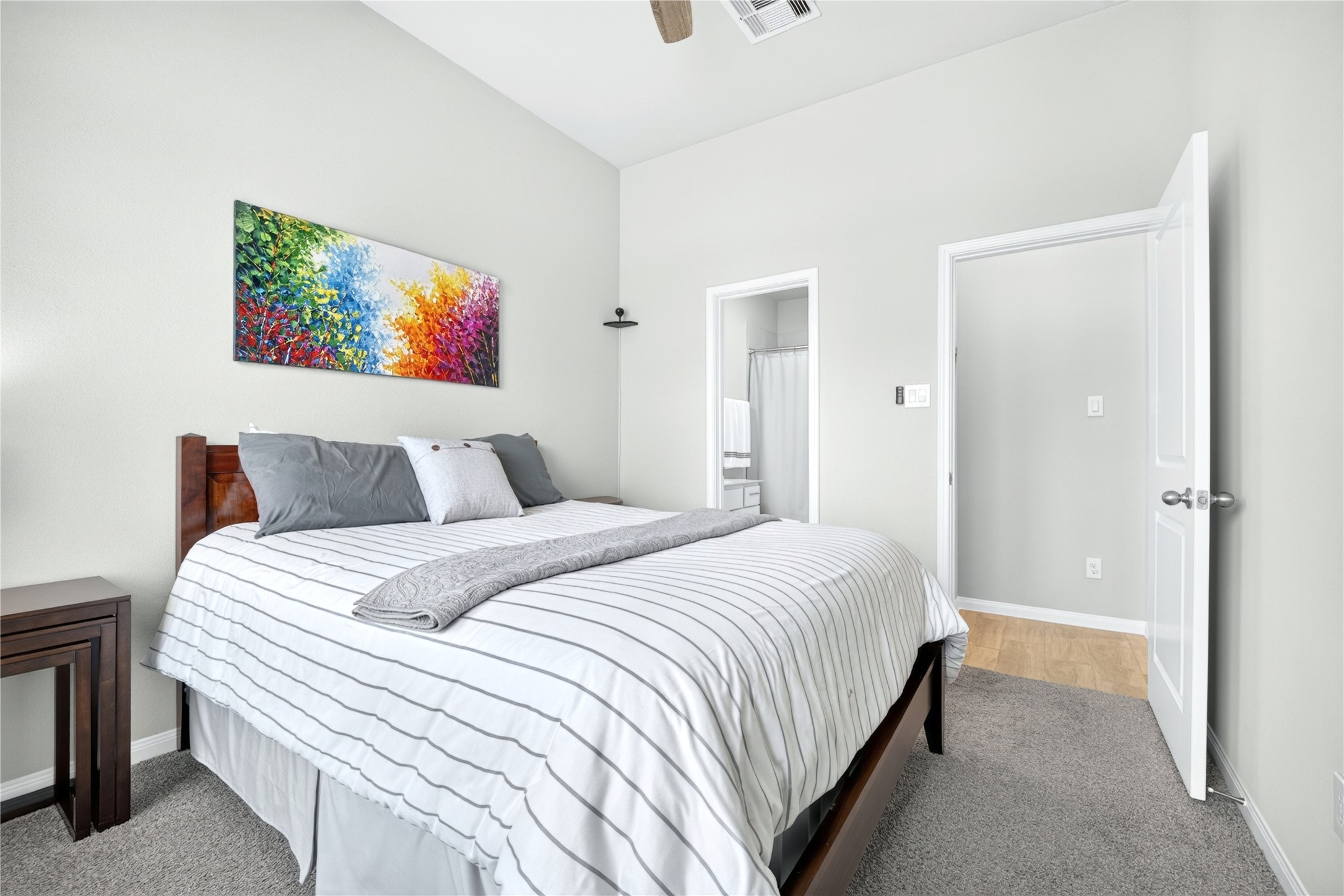 One of the front bedrooms featuring stylish en-suite bath, single vanity, soaking tub, designer mirror and spacious walk-in closet. Sophisticated gray tones create serene retreat.