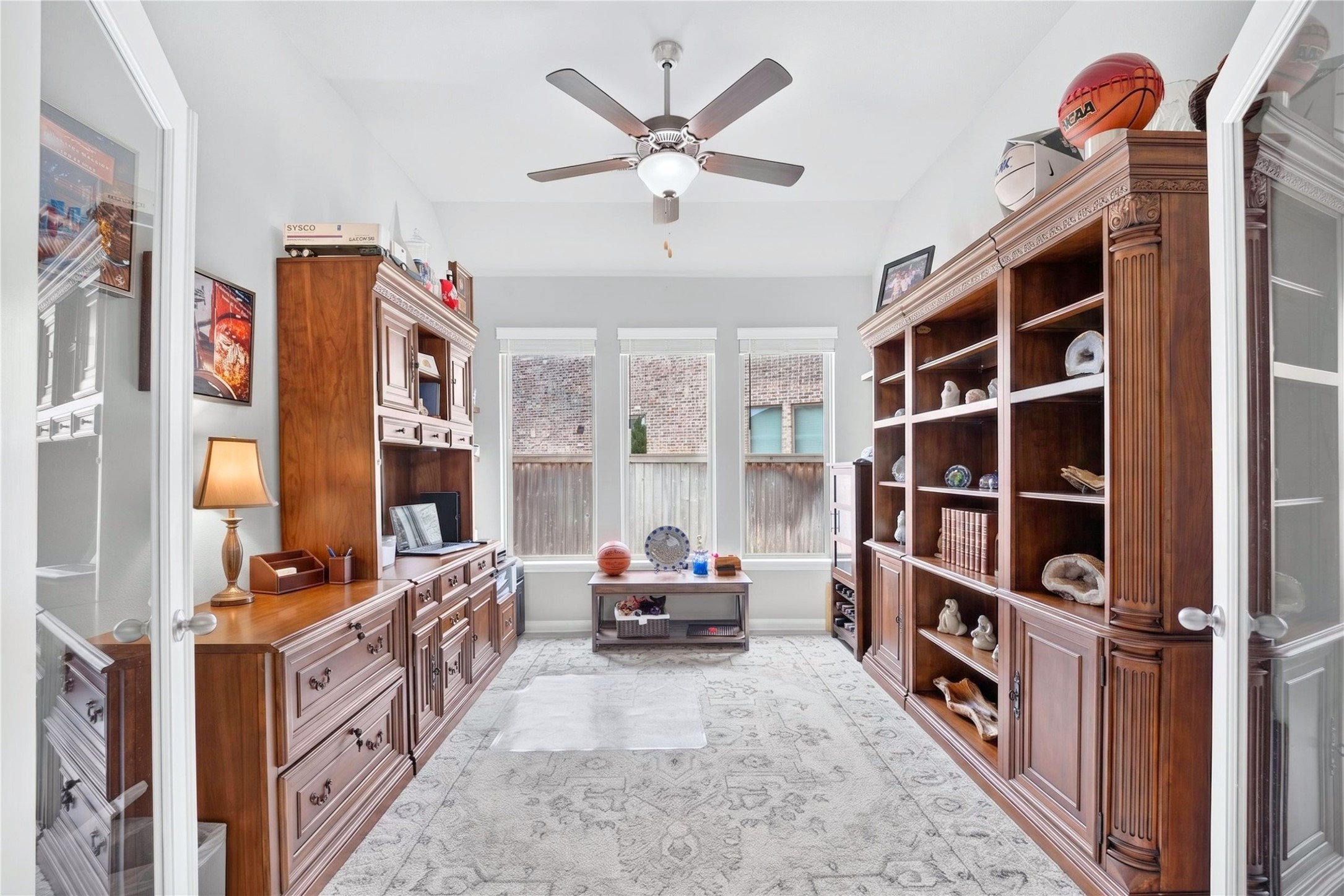 Private home office tucked toward the center of the home, featuring double glass doors and windows that bring in natural light.